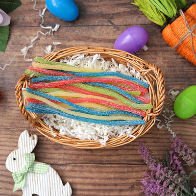 Sour Punch Rainbow Straws candy in an Easter basket surrounded by confetti and plastic eggs