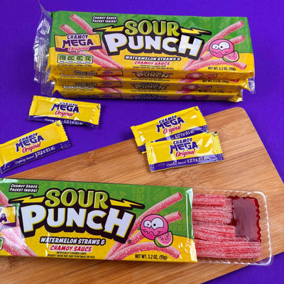 Open Sour Punch candy tray with Chamoy sauce on a wooden surface with a purple background
