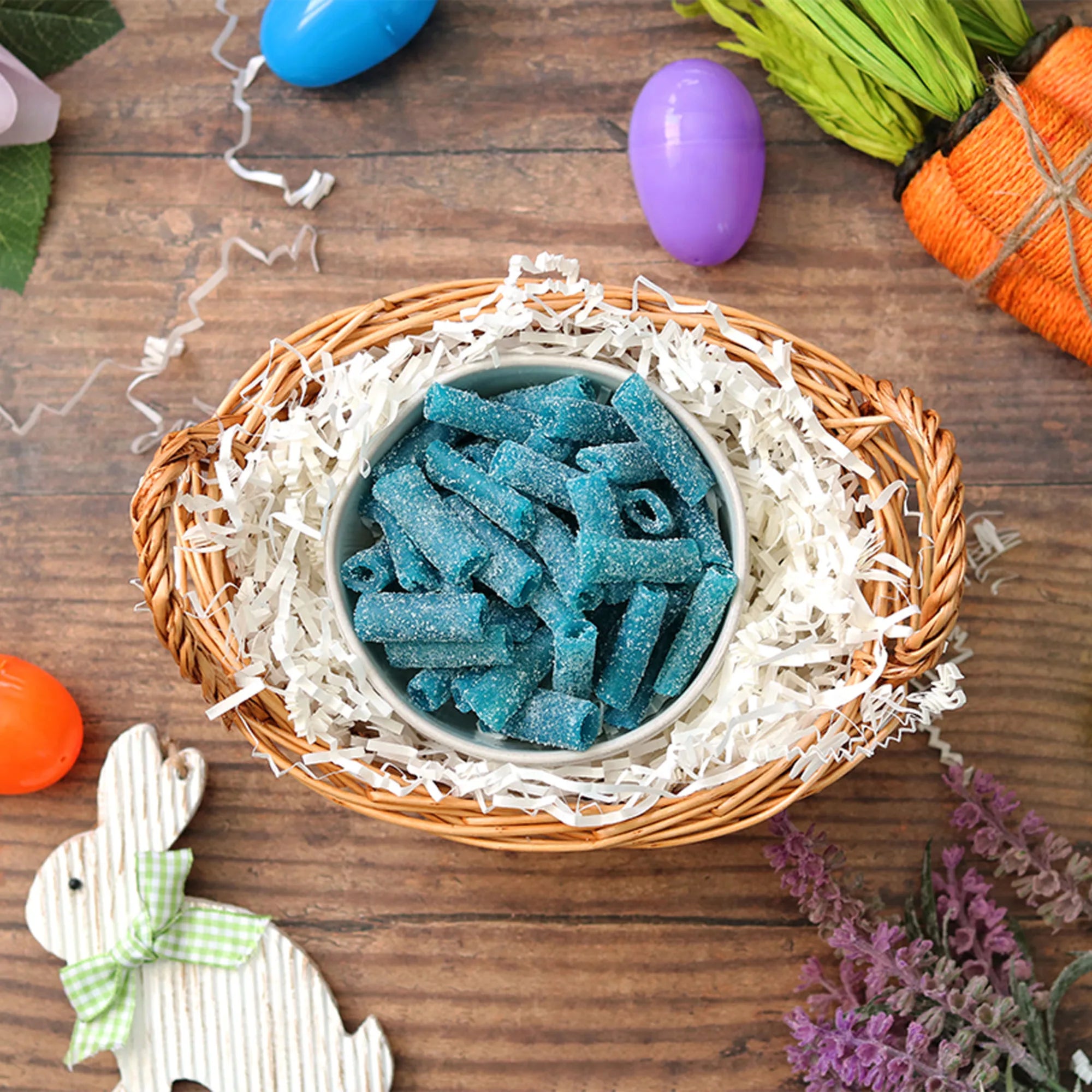 Sour Punch Blue Raspberry Bites candy in an Easter basket surrounded by confetti and plastic eggs