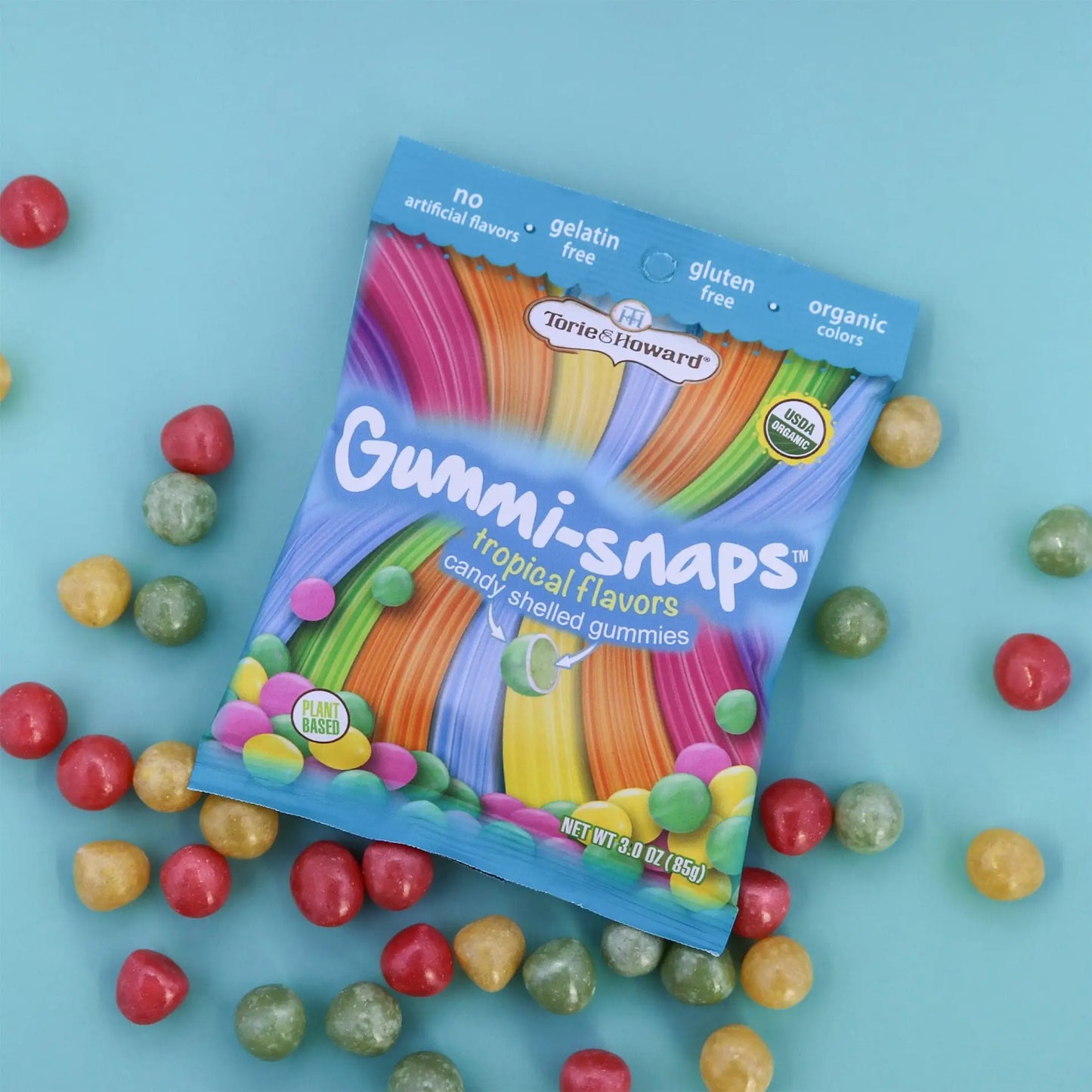 Cylindrical shaped red, yellow, and green candy scattered around a Torie & Howard Gummi-Snaps Tropical Flavors Bag