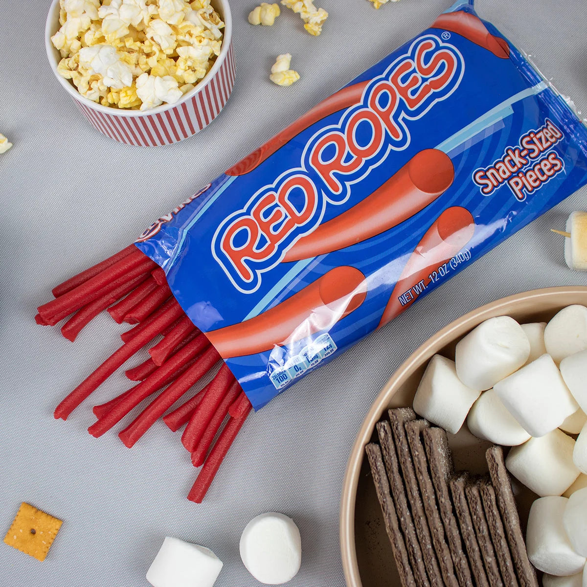 Open bag of Red Vines Red Ropes with a bowl of popcorn and s'mores ingredients