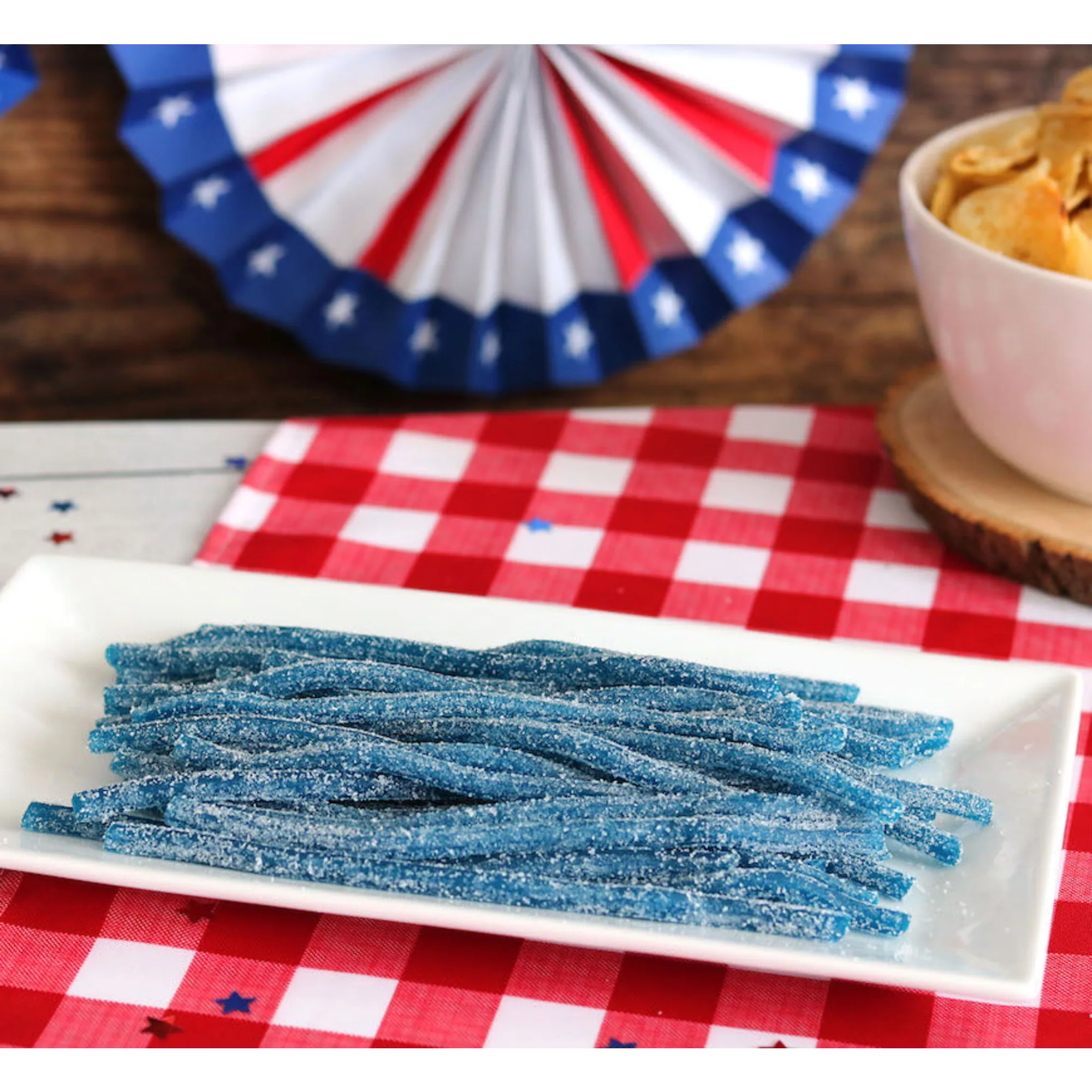Sour Punch Blue Raspberry Straws Candy on a picnic table with patriotic decorations