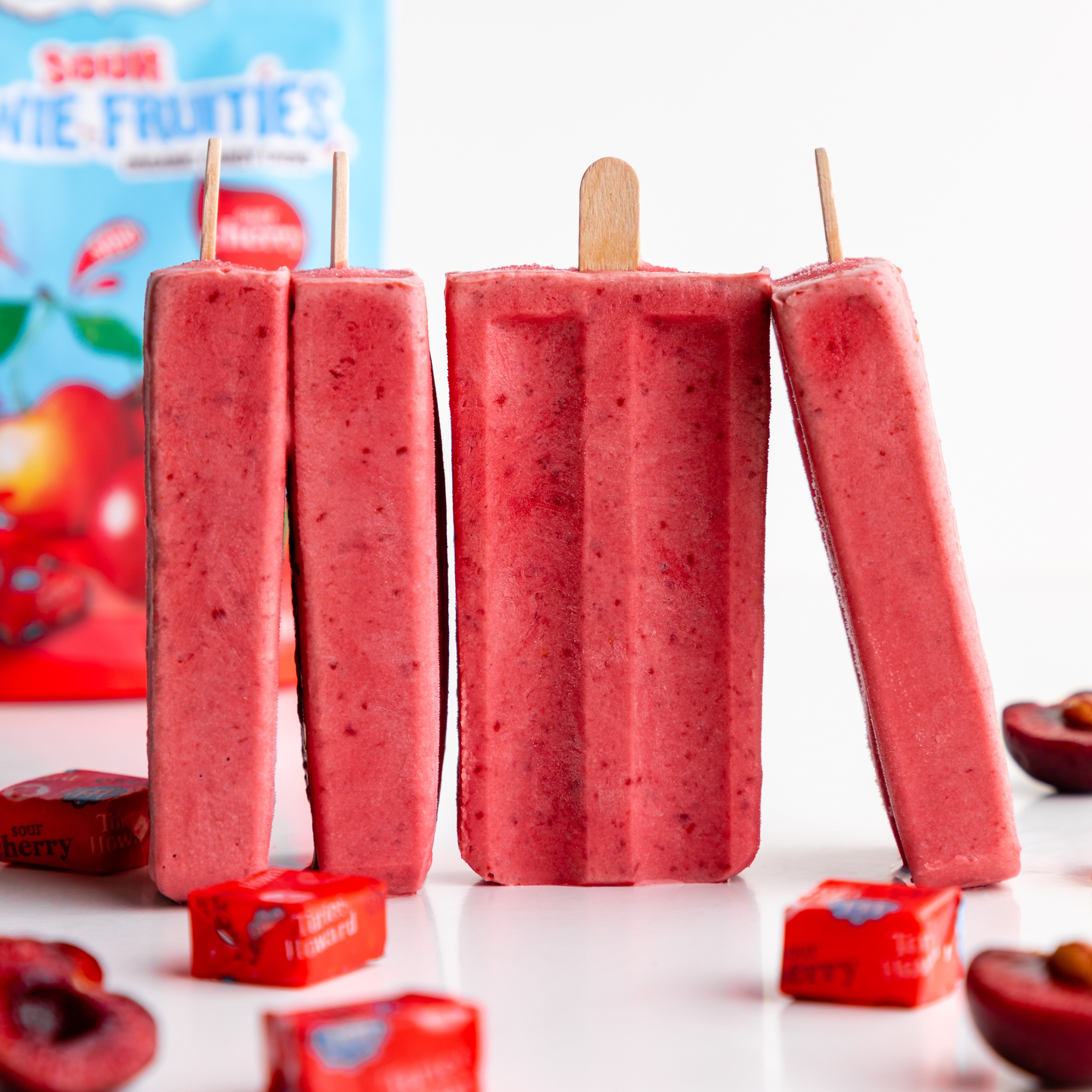 Torie & Howard Sour Cherry Popsicles on a white counter with Sour Cherry Chewie Fruities