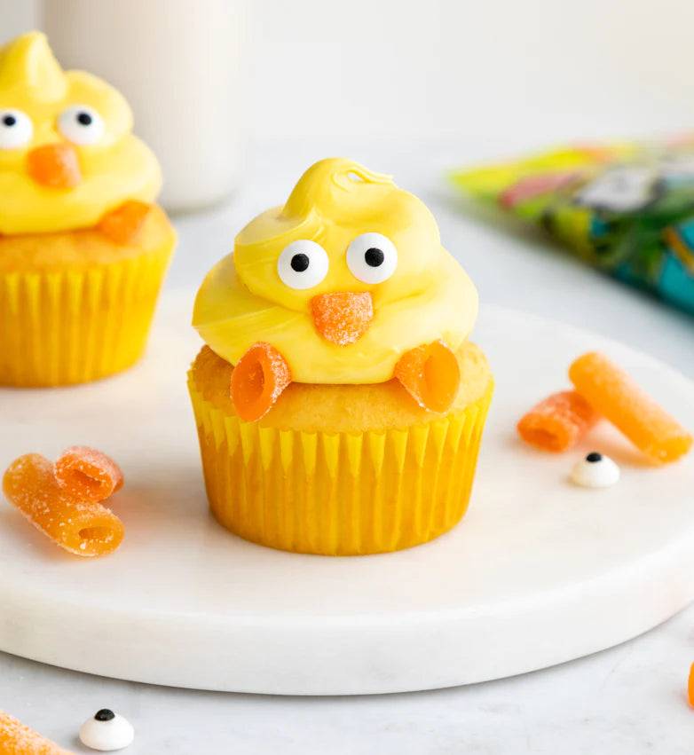 Easter Cupcakes with yellow frosting, Sour Punch Tropical Candy Bites for the beak and feet, and candy eyes to make it look like a chick is sitting on top