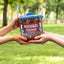 Two people passing a Red Vines Original Red Licorice Candy Twists 3.5lb Jar in limited-edition football graphics