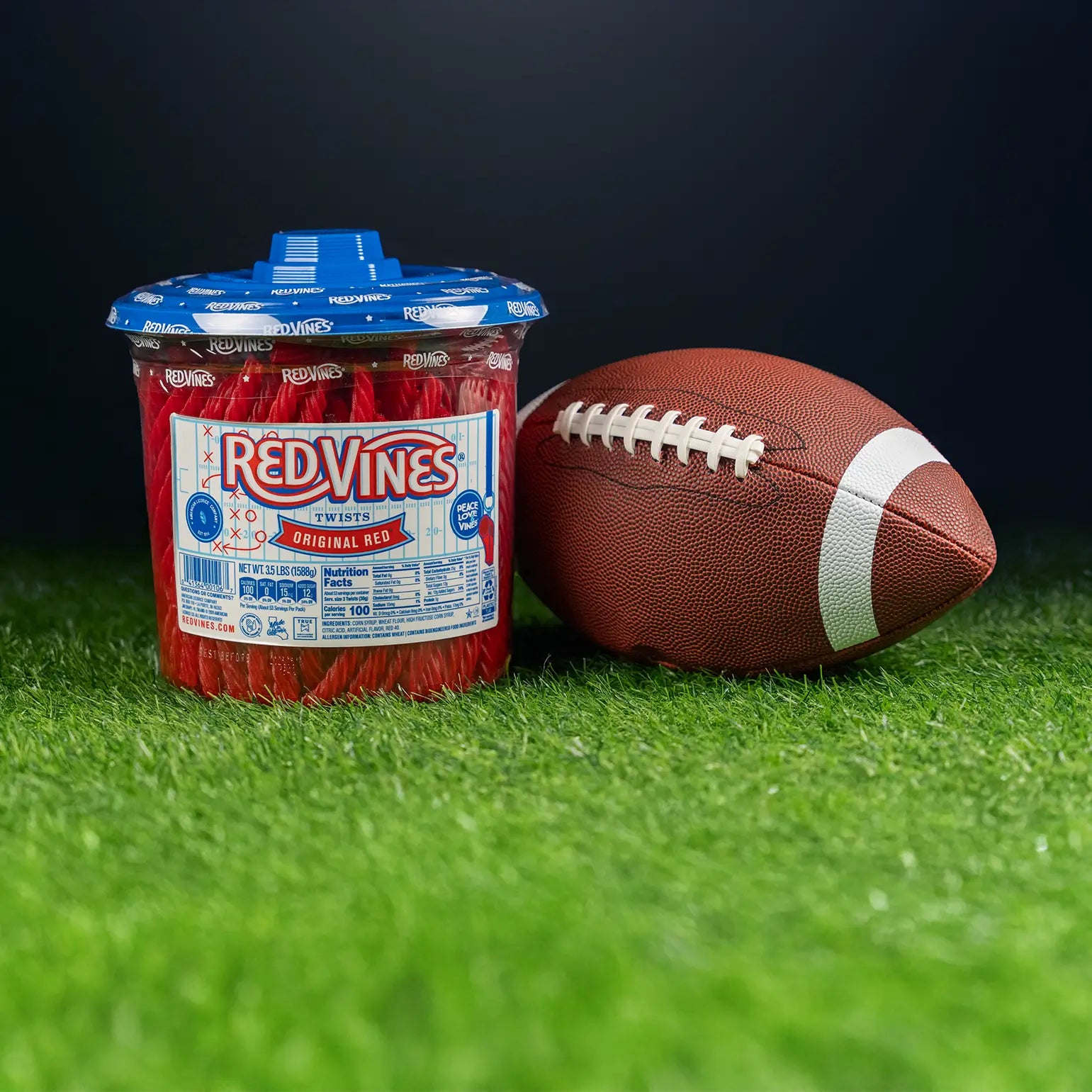 3.5lb Jar of RED VINES Original Red Licorice Candy (with limited edition football-themed label) sitting on turf next to a football