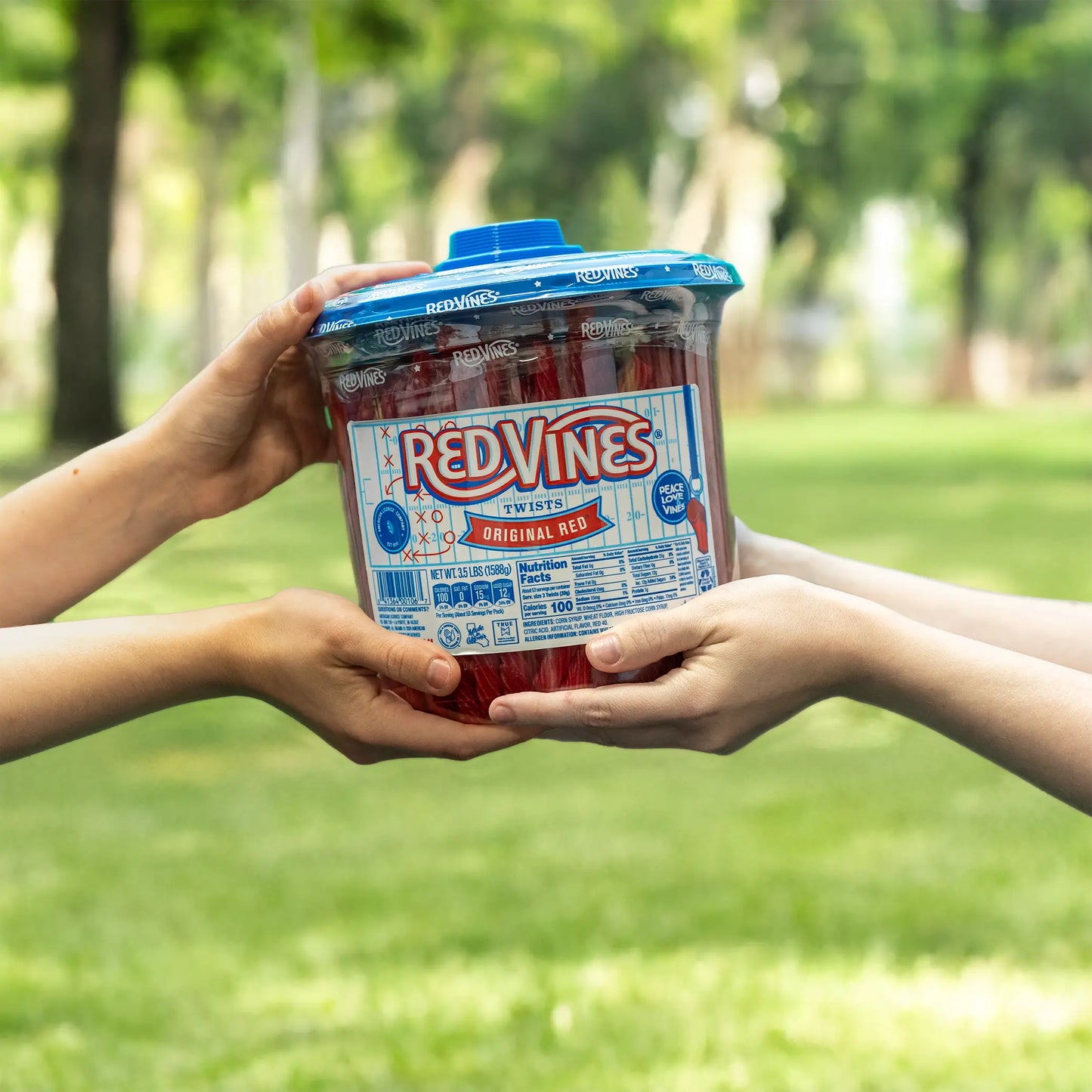 3.5lb Jar of RED VINES Original Red Licorice Candy (with limited edition football-themed label) being passed between two people