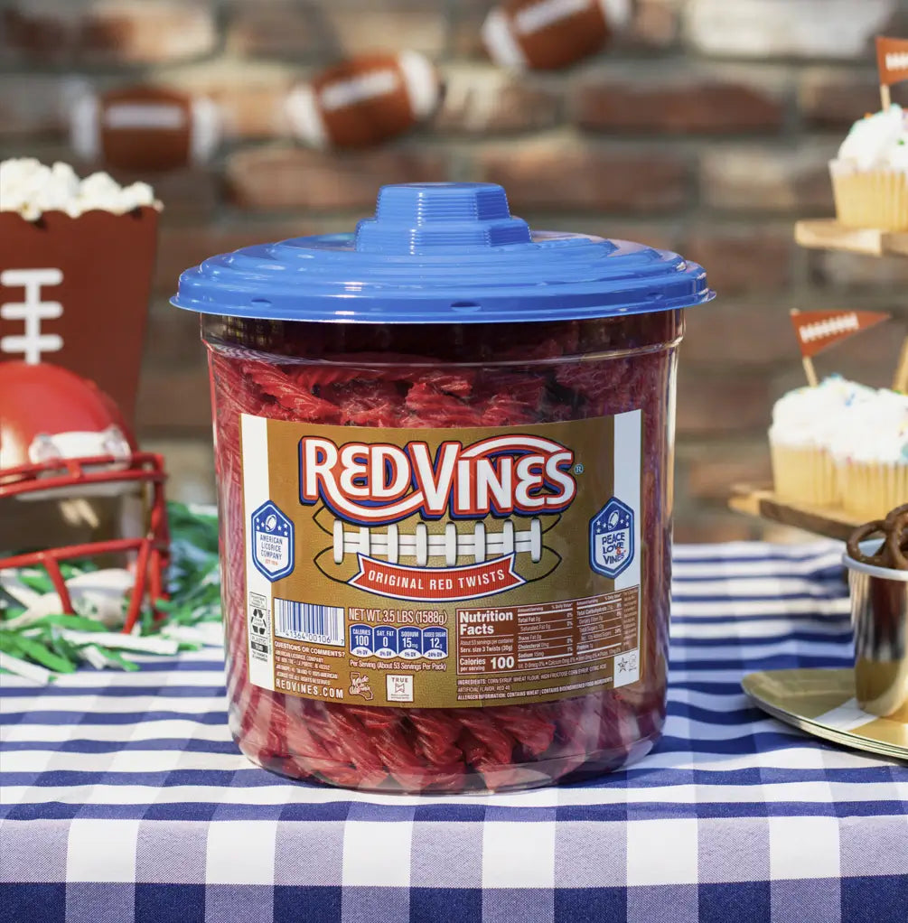 Red Vines Original Red Licorice Twists 3.5lb Jar in limited-edition football graphics sitting on a picnic table with game day snacks and decor