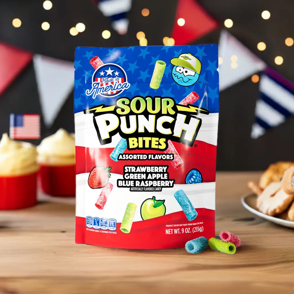 Front of Sour Punch Assorted Americana Candy Bites 9oz bag surrounded by 4th of July decorations and deserts