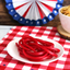 Super Ropes Red Licorice Rope Candy on a picnic table with other snacks and patriotic decorations
