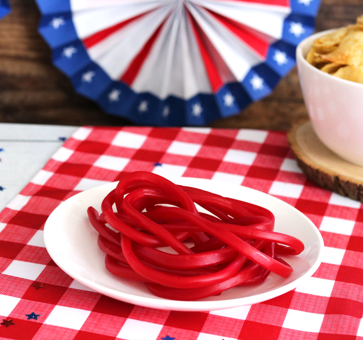 Super Ropes Red Licorice Rope Candy on a picnic table with other snacks and patriotic decorations