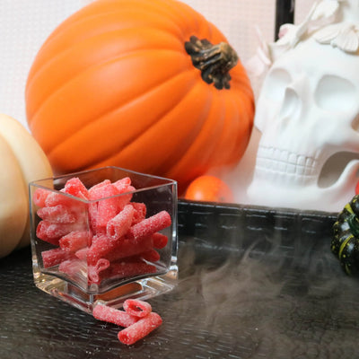 Sour Punch Strawberry Bites Candy on a black tray with pumpkins and fake skulls