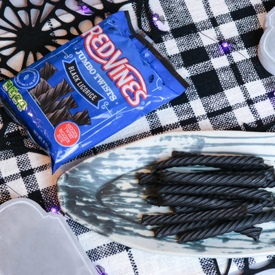 Red Vines Jumbo Black Licorice Candy on a platter with a fake spiderweb and tombstone