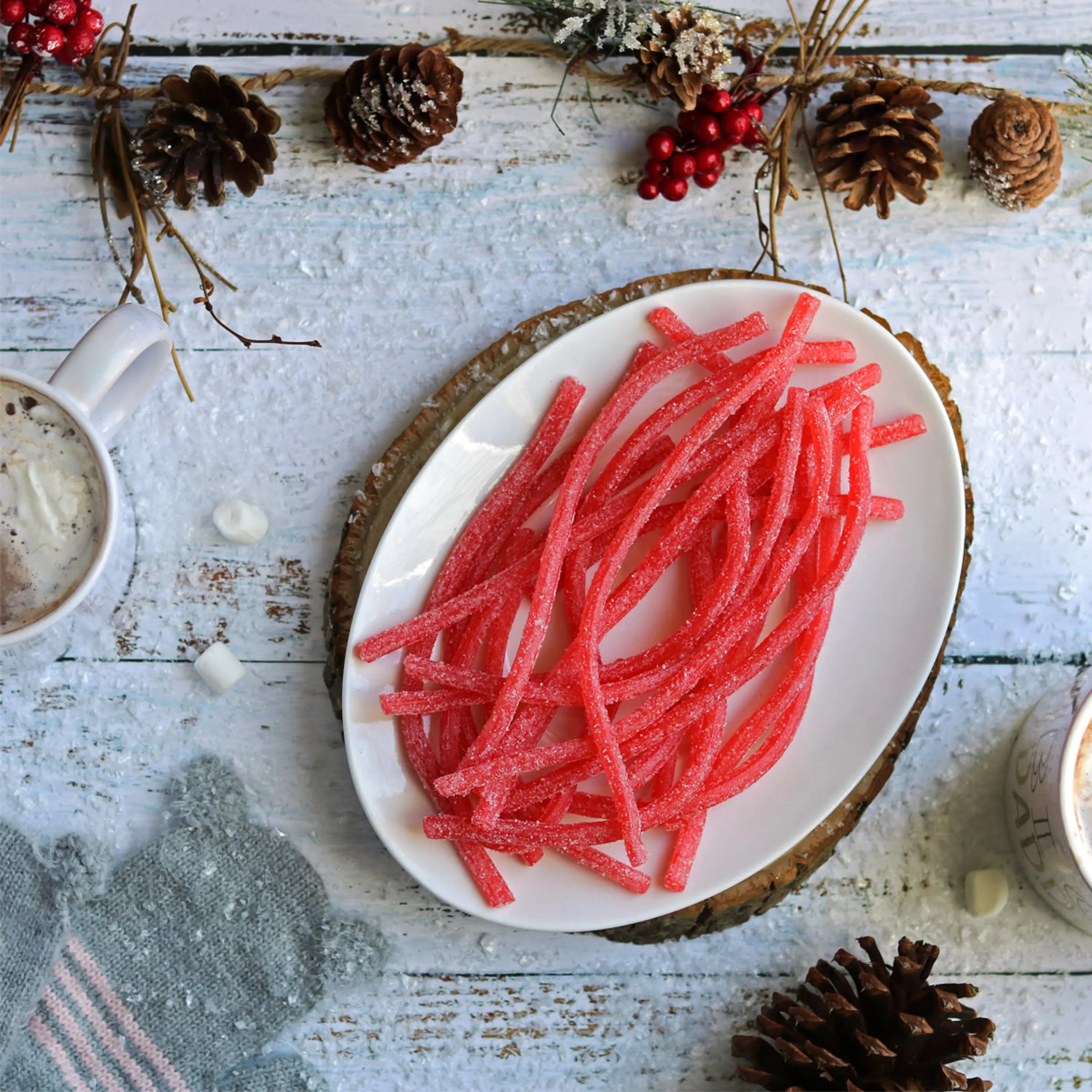 Sour Strawberry Straws on a festive dish with a cup of hot cocoa