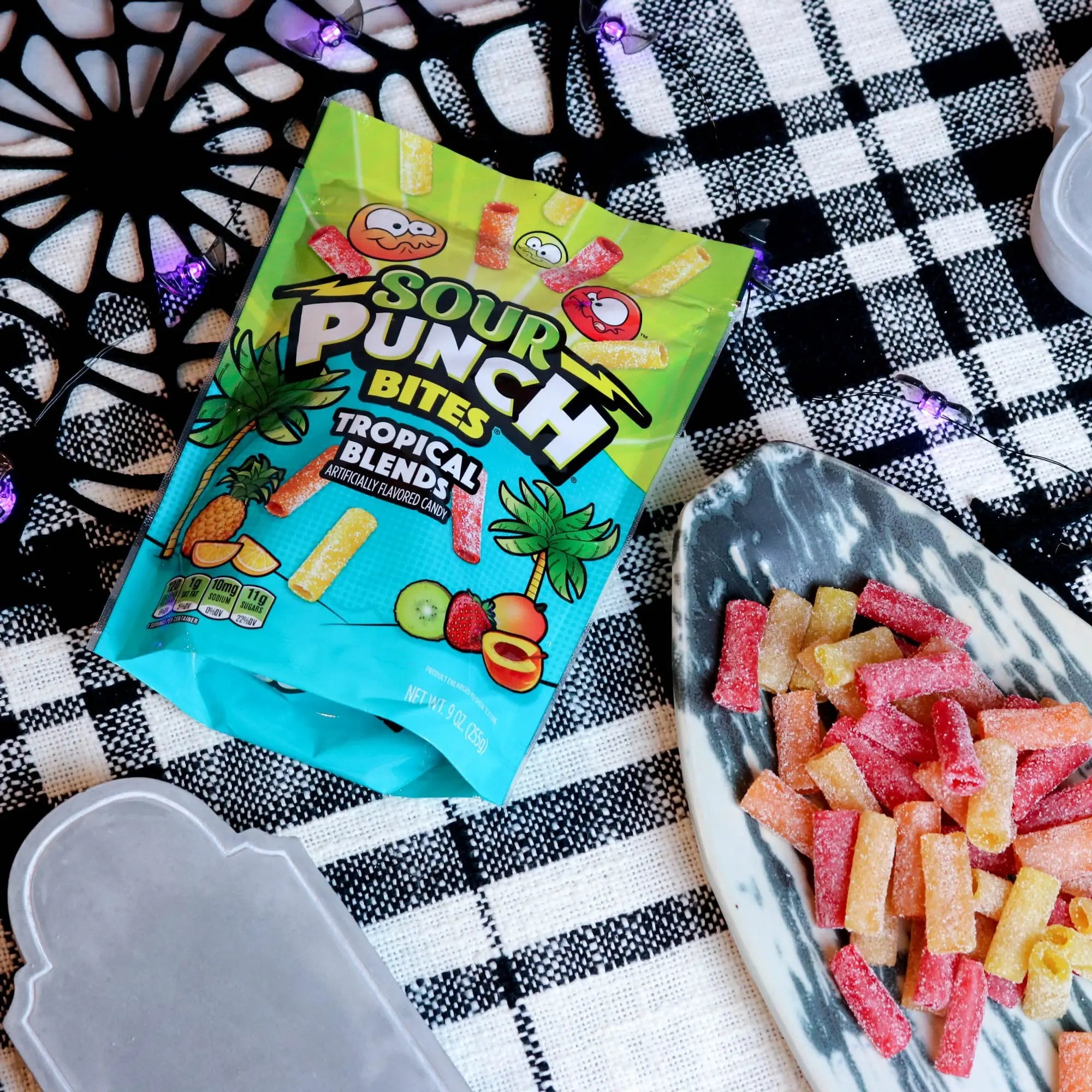 Sour Punch Tropical Bites Candy on a platter with a fake spiderweb and tombstone