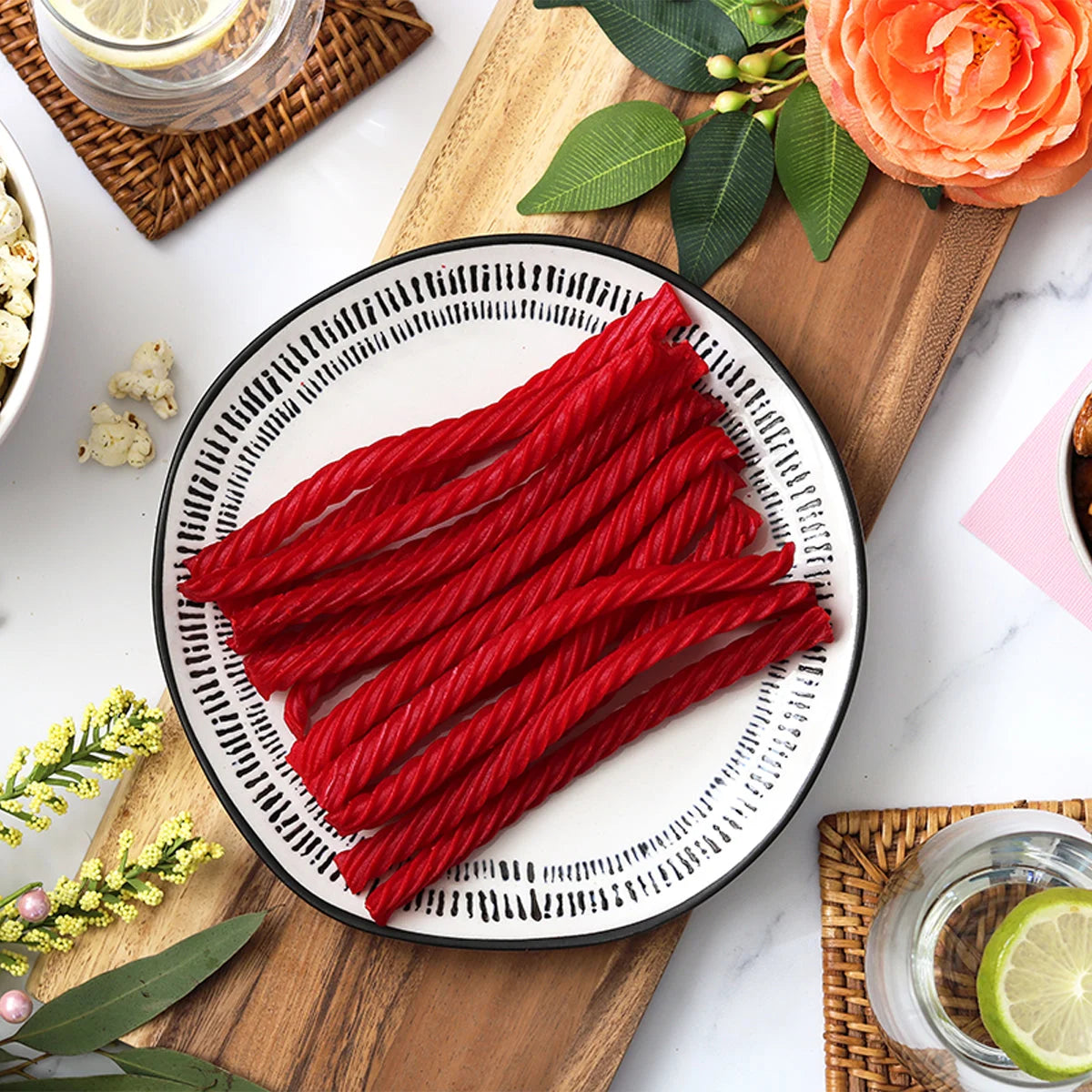 Red Vines Original Red Licorice Twists candy  on a plate surrounded by spring flowers and other snacks