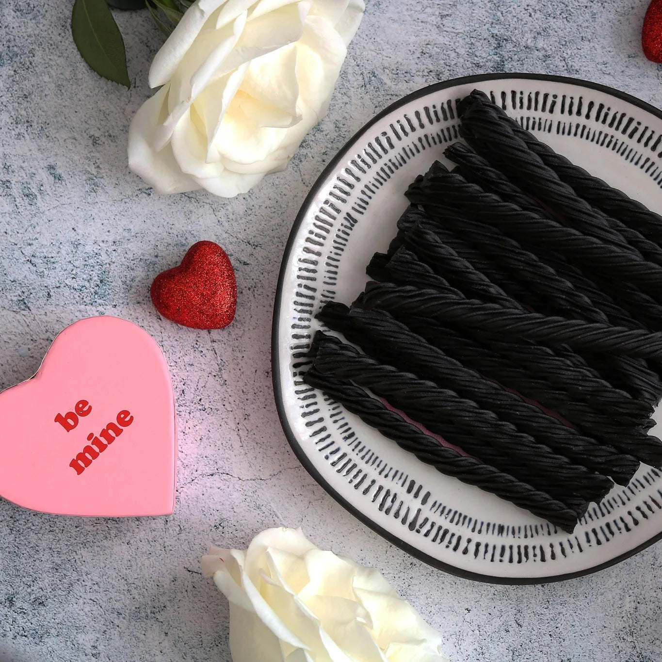 RED VINES Black Licorice Twists surrounded by white roses and a "be mine" heart shaped box