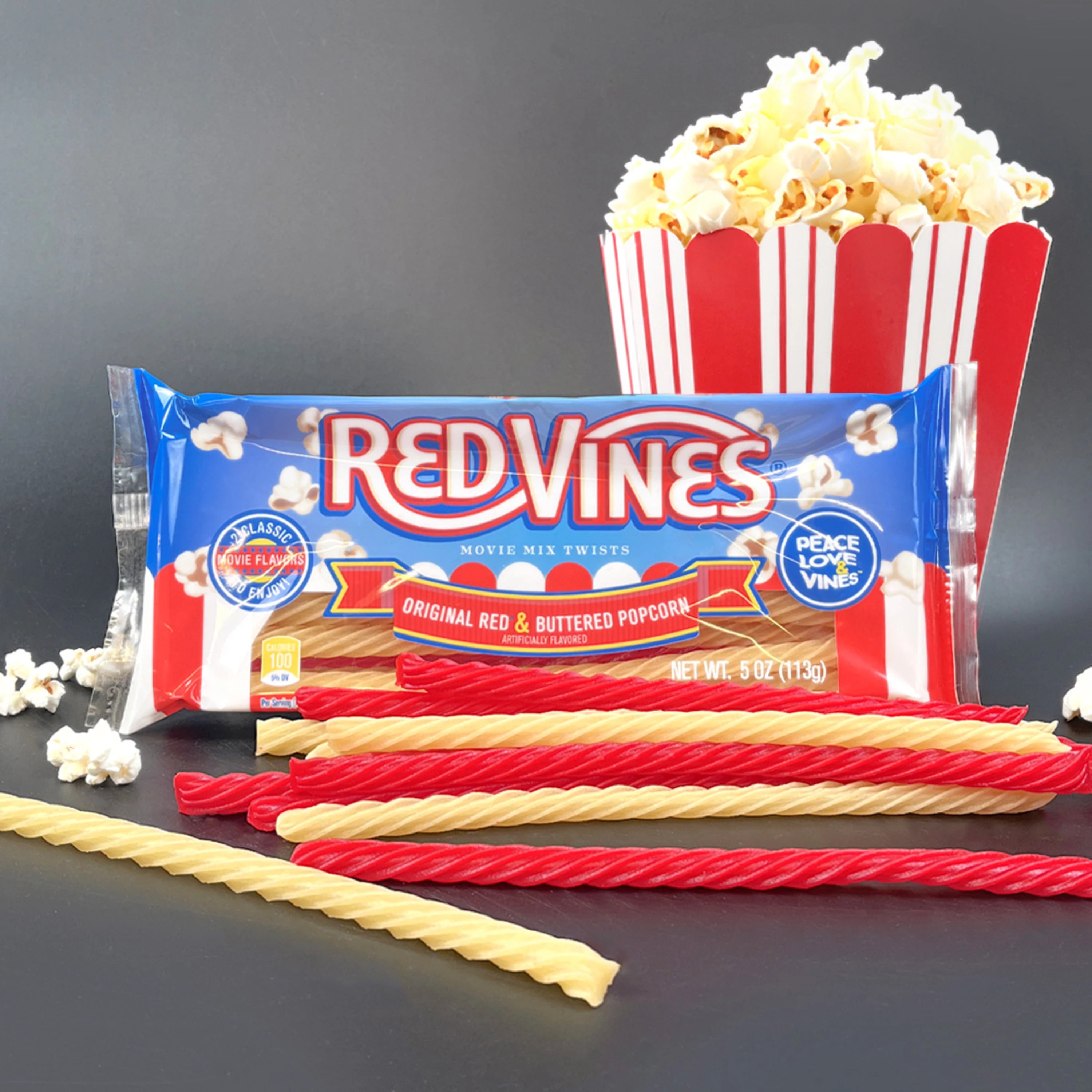 Red Vines Buttered Popcorn & Original Red Twists on gray background with bucket of popcorn