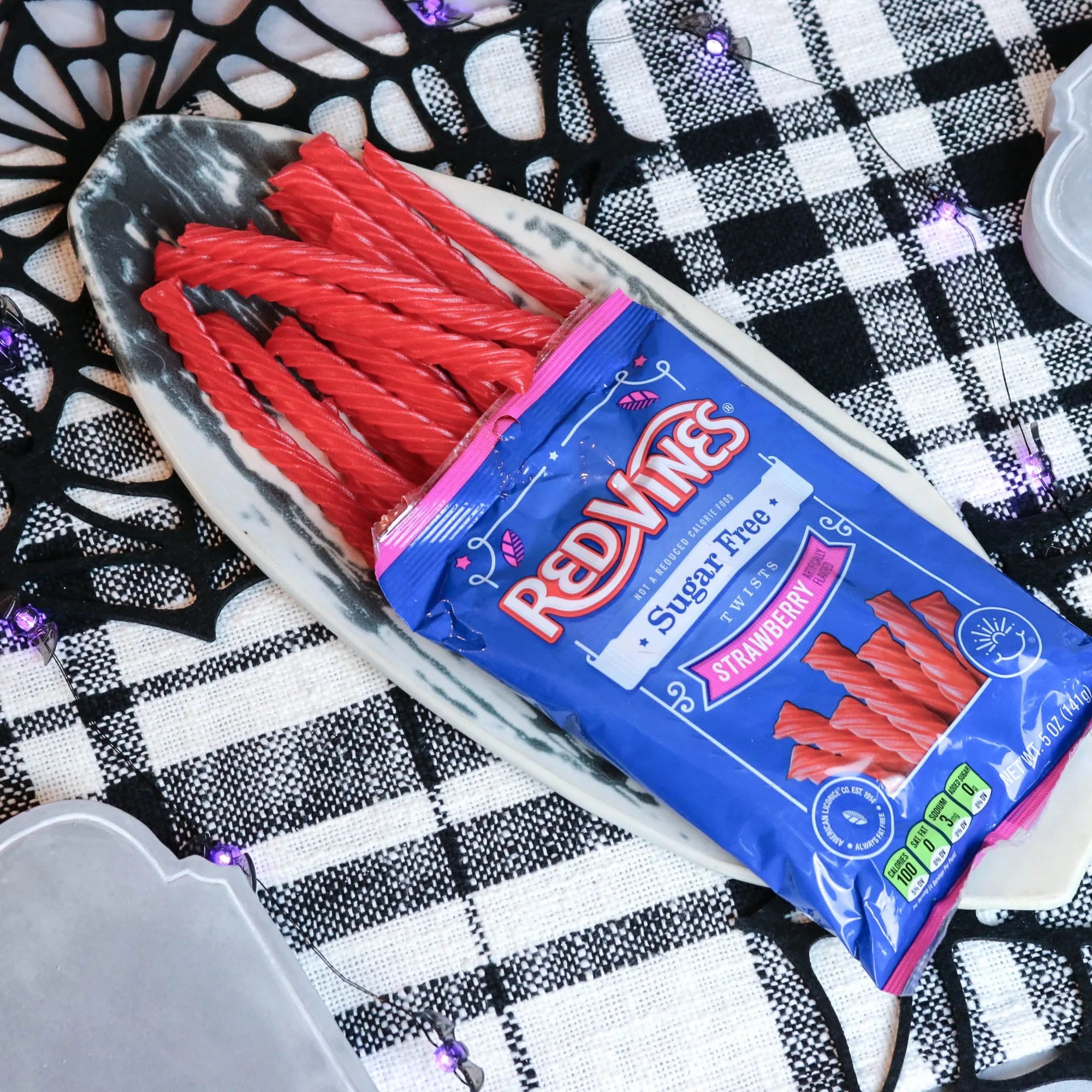 Red Vines Strawberry Sugar Free Licorice on a platter with a fake spiderweb and tombstone