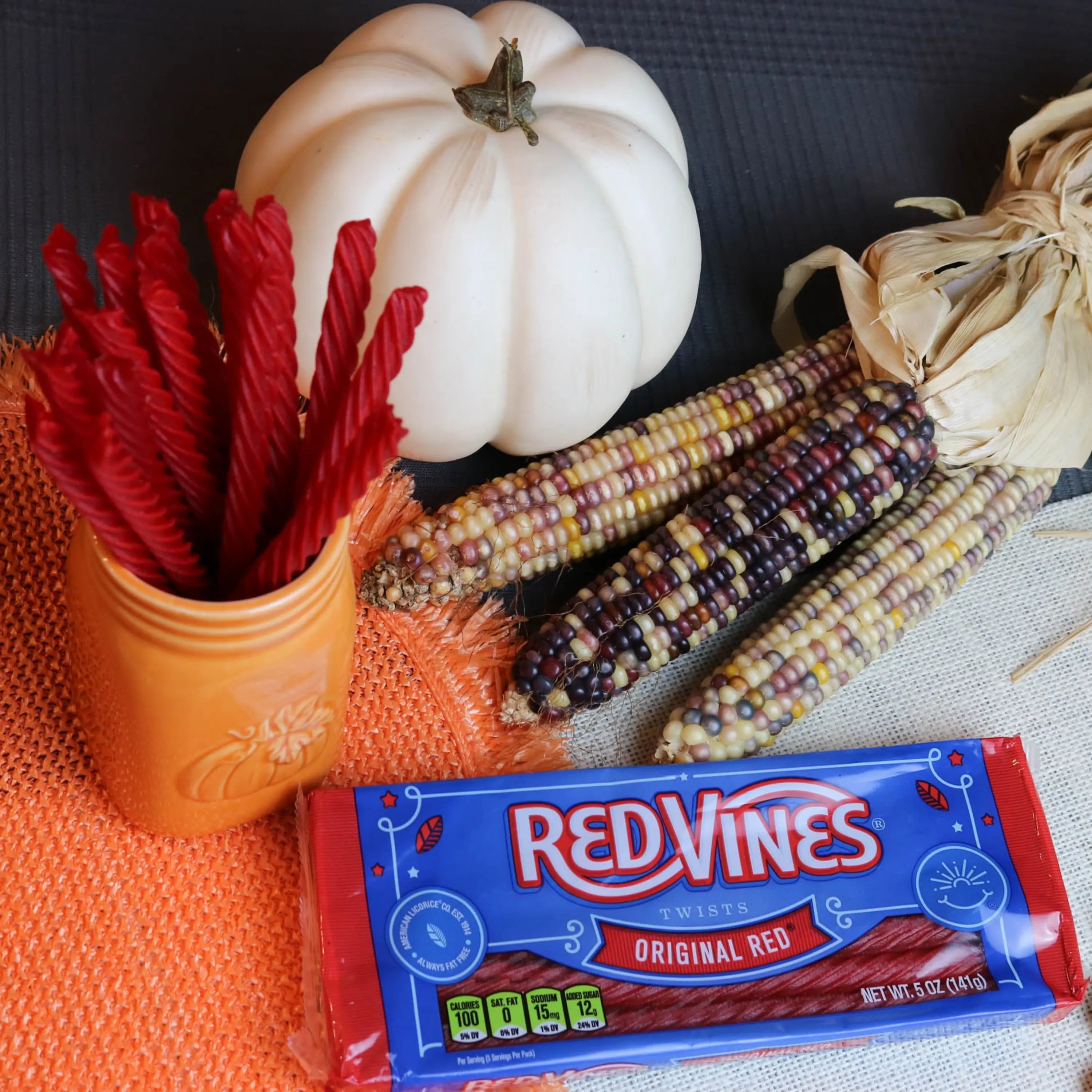 Red Vines Original Red Licorice Candy in an orange mug near a pumpkin and falltime props