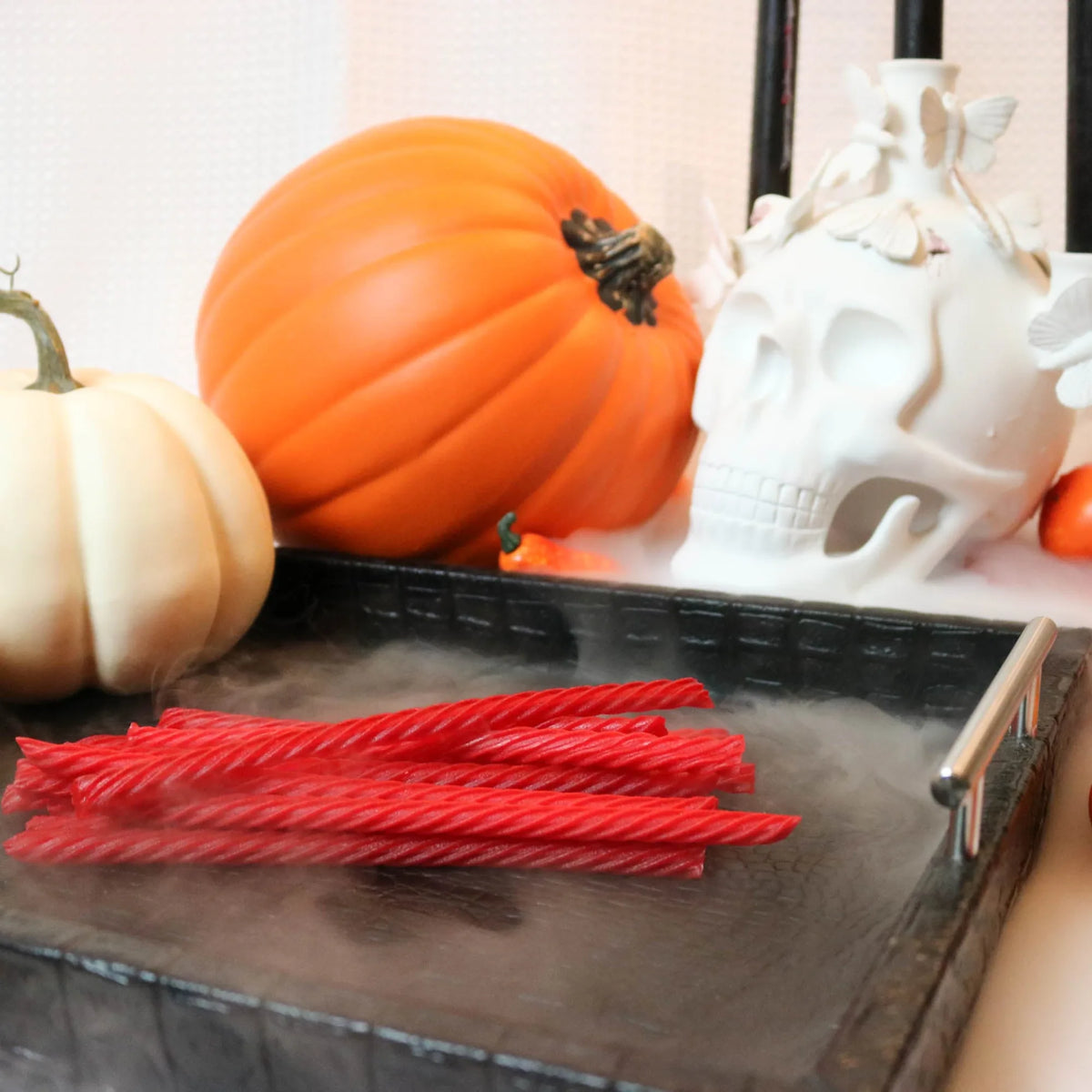 Red Vines Original Red Licorice Candy on a black platter with pumpkins and fake skulls