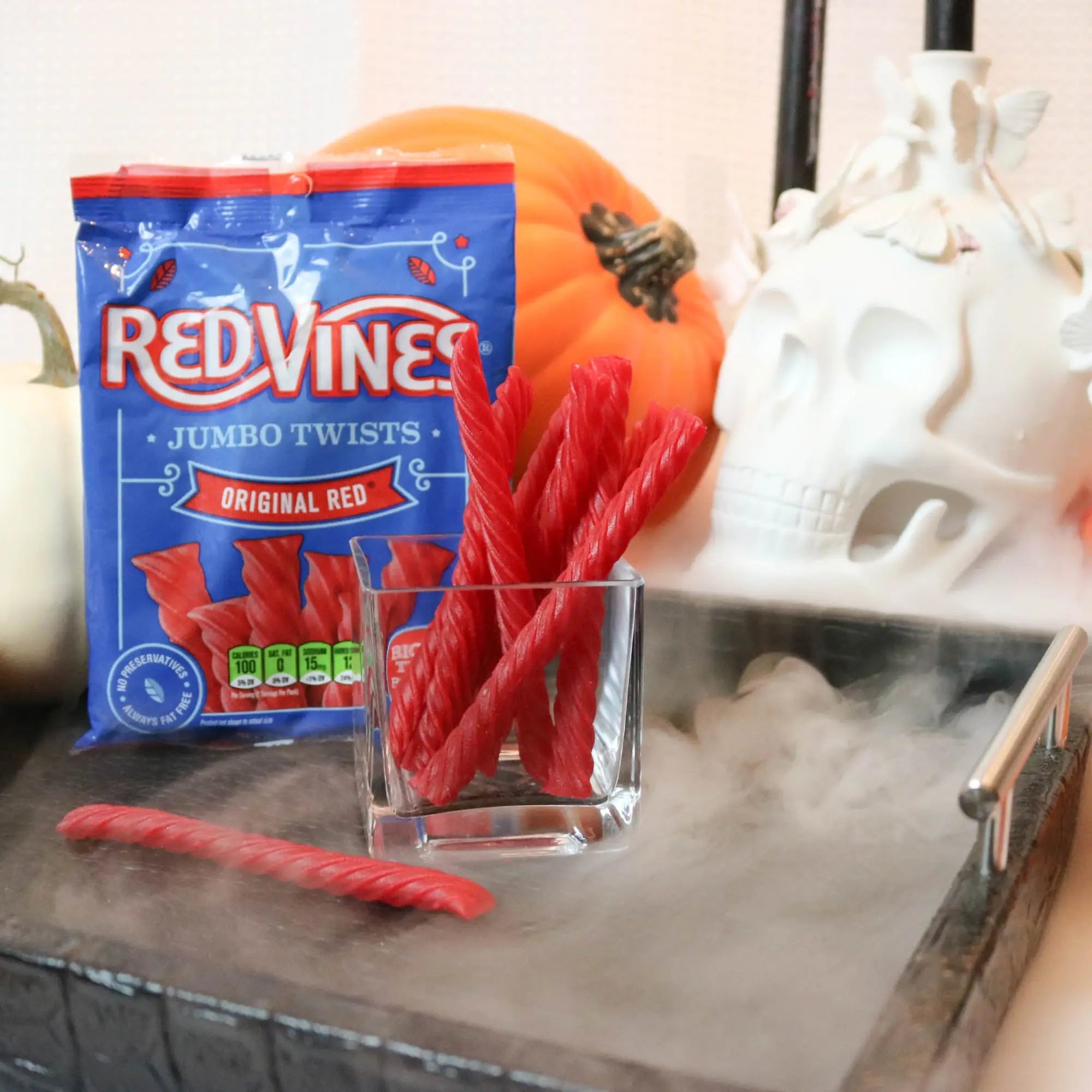 Red Vines Original Red Jumbo Licorice Twists on a black platter with pumpkins and fake skulls
