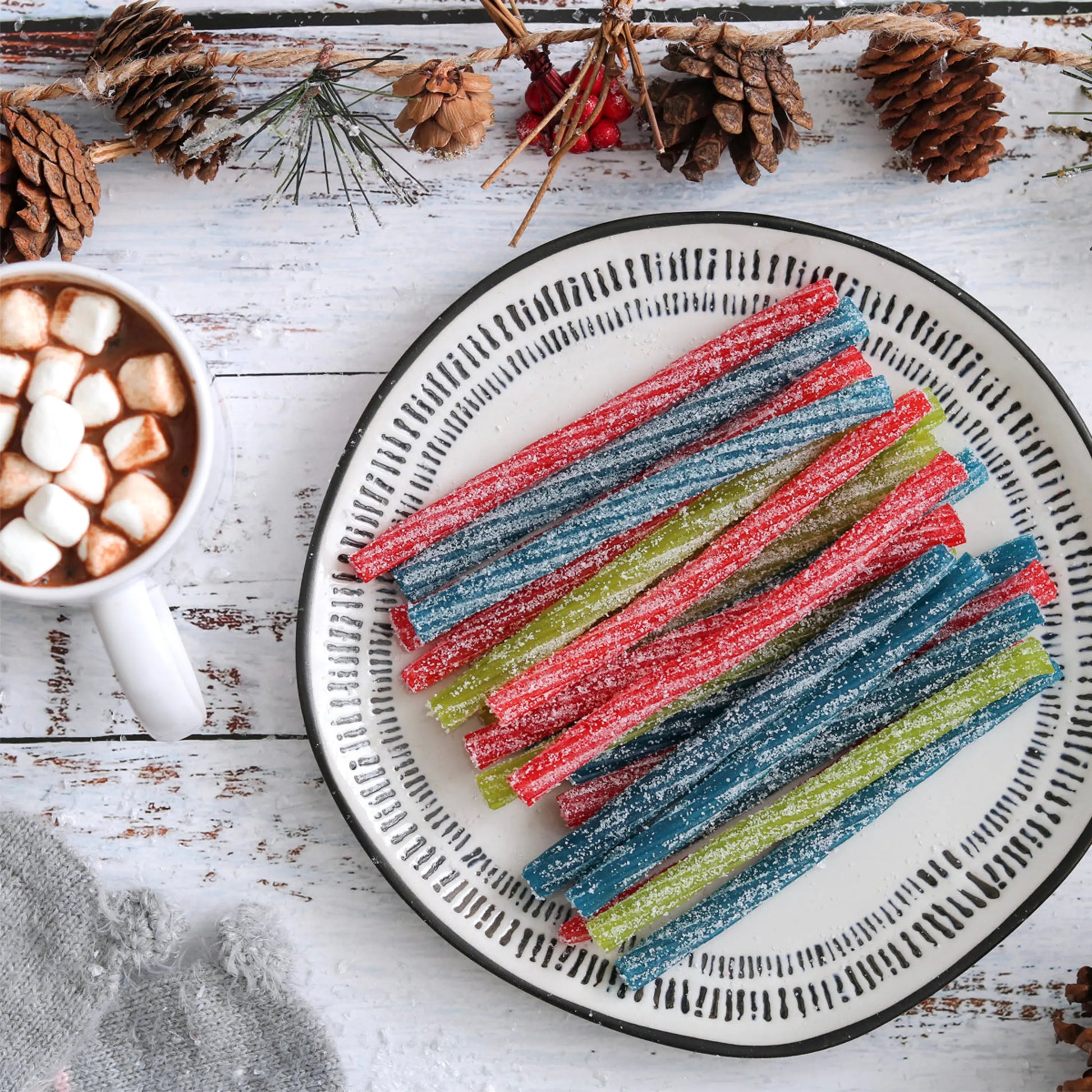 6" Assorted Sour Candy Twists on a plate with a cup of hot cocoa