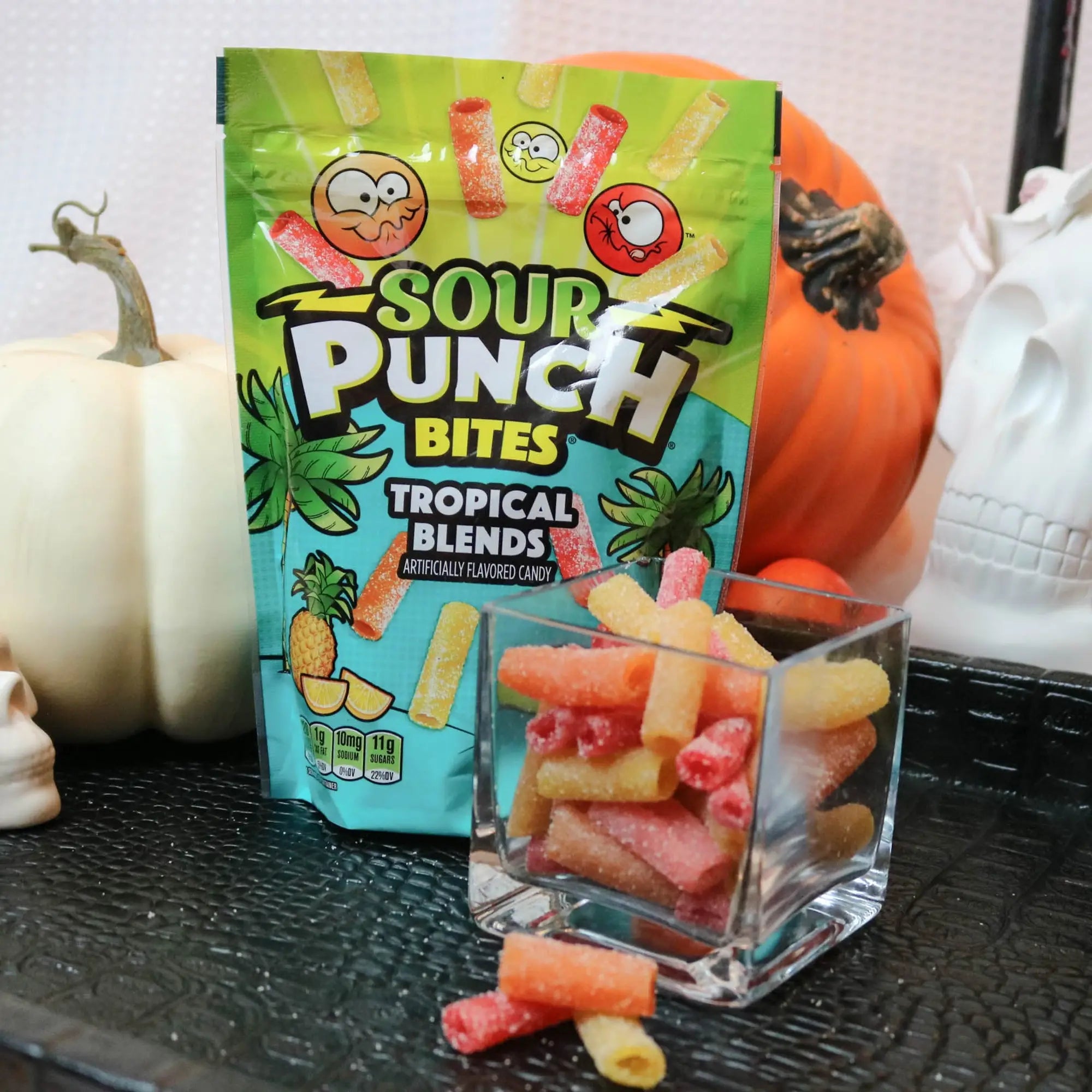 Sour Punch Tropical Bites Candy on a black tray with pumpkins and fake skulls