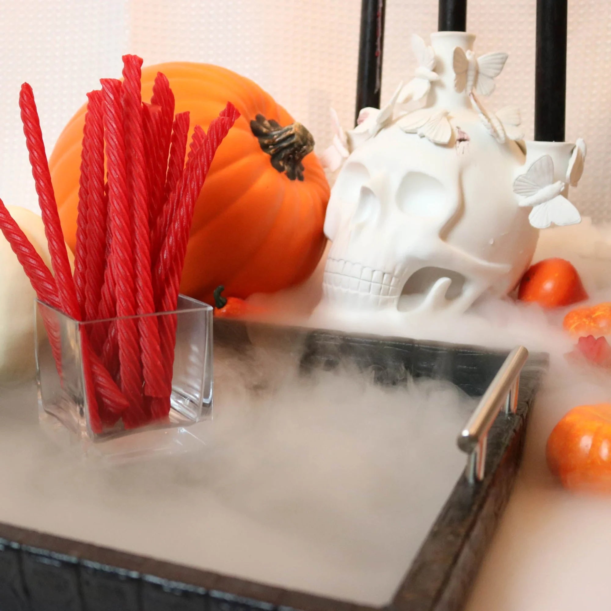 Red Vines Original Red Licorice Candy on a black platter with pumpkins and fake skulls