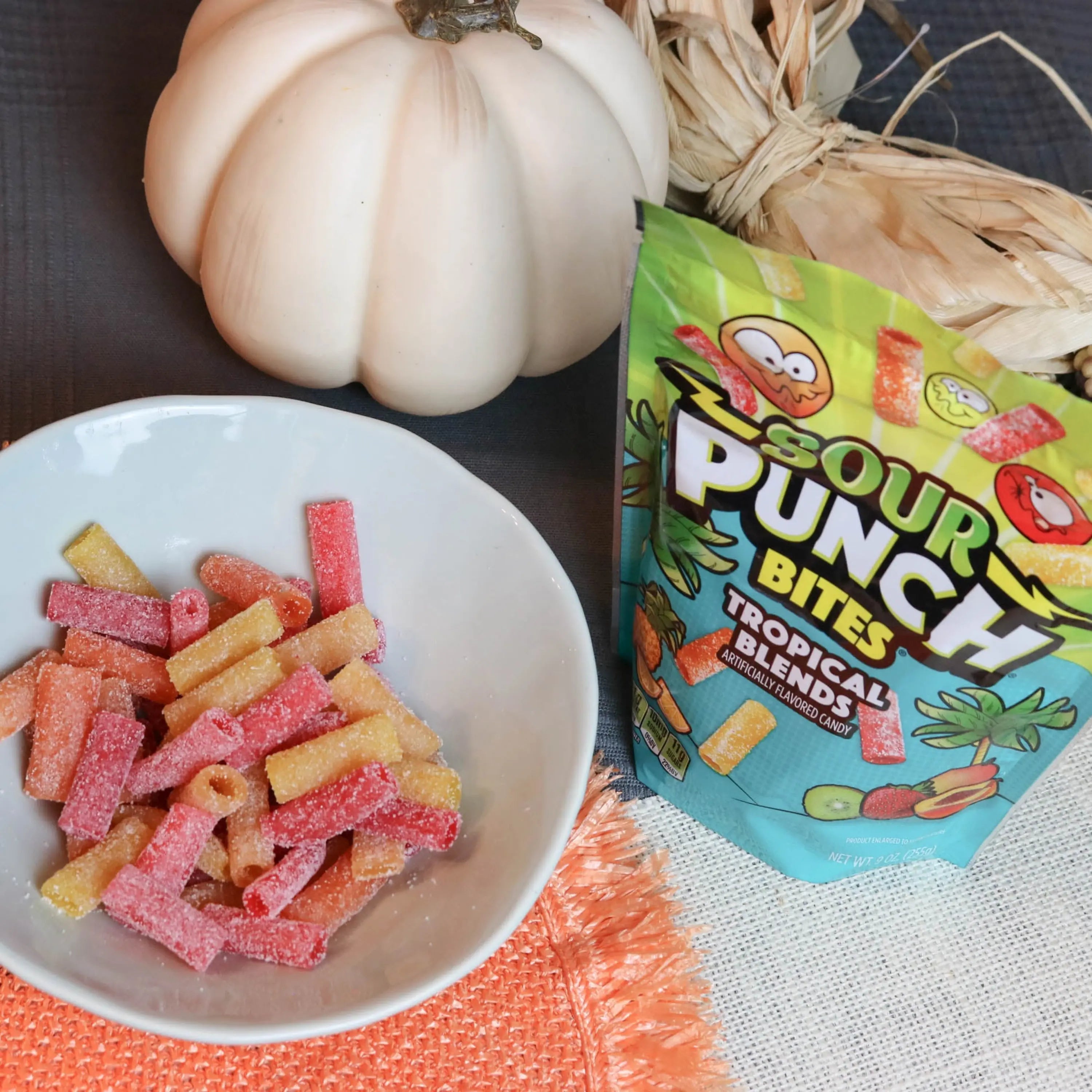 Sour Punch Tropical Bites Candy in a white dish near a pumpkin and falltime props