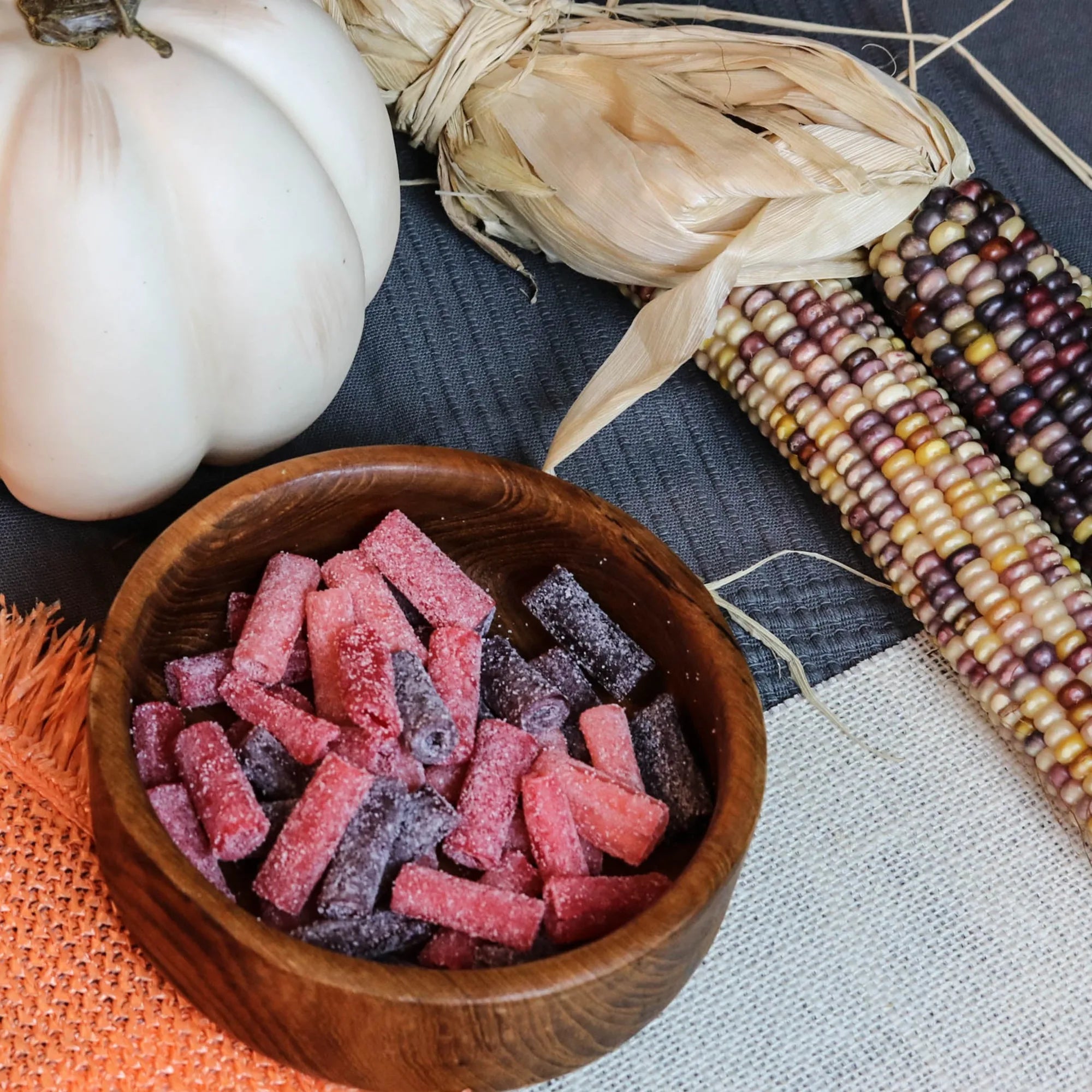 Sour Punch Rad Red Bites Candy in a wooden dish near a pumpkin and falltime props