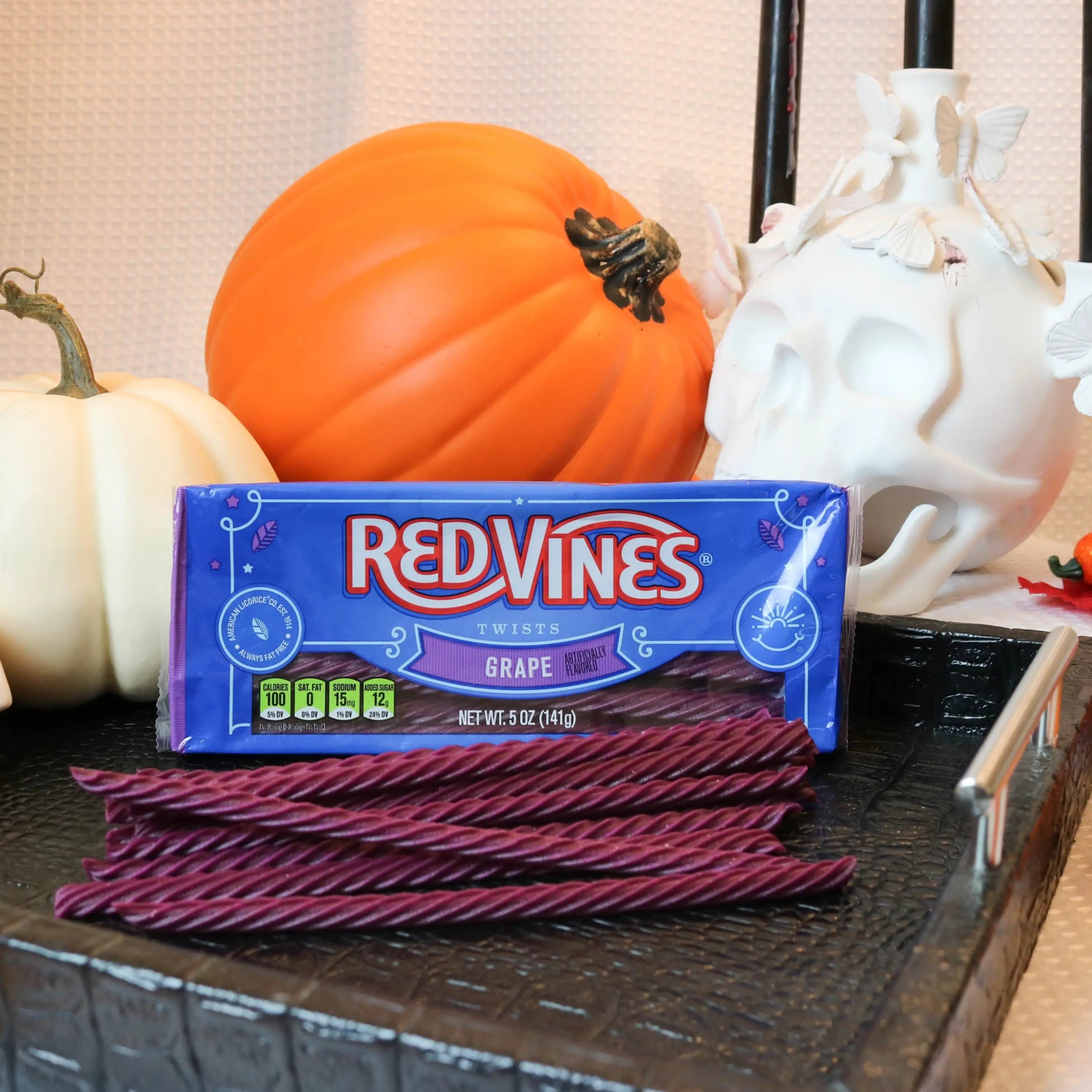 Red Vines Grape Licorice Candy on a black platter with pumpkins and fake skulls