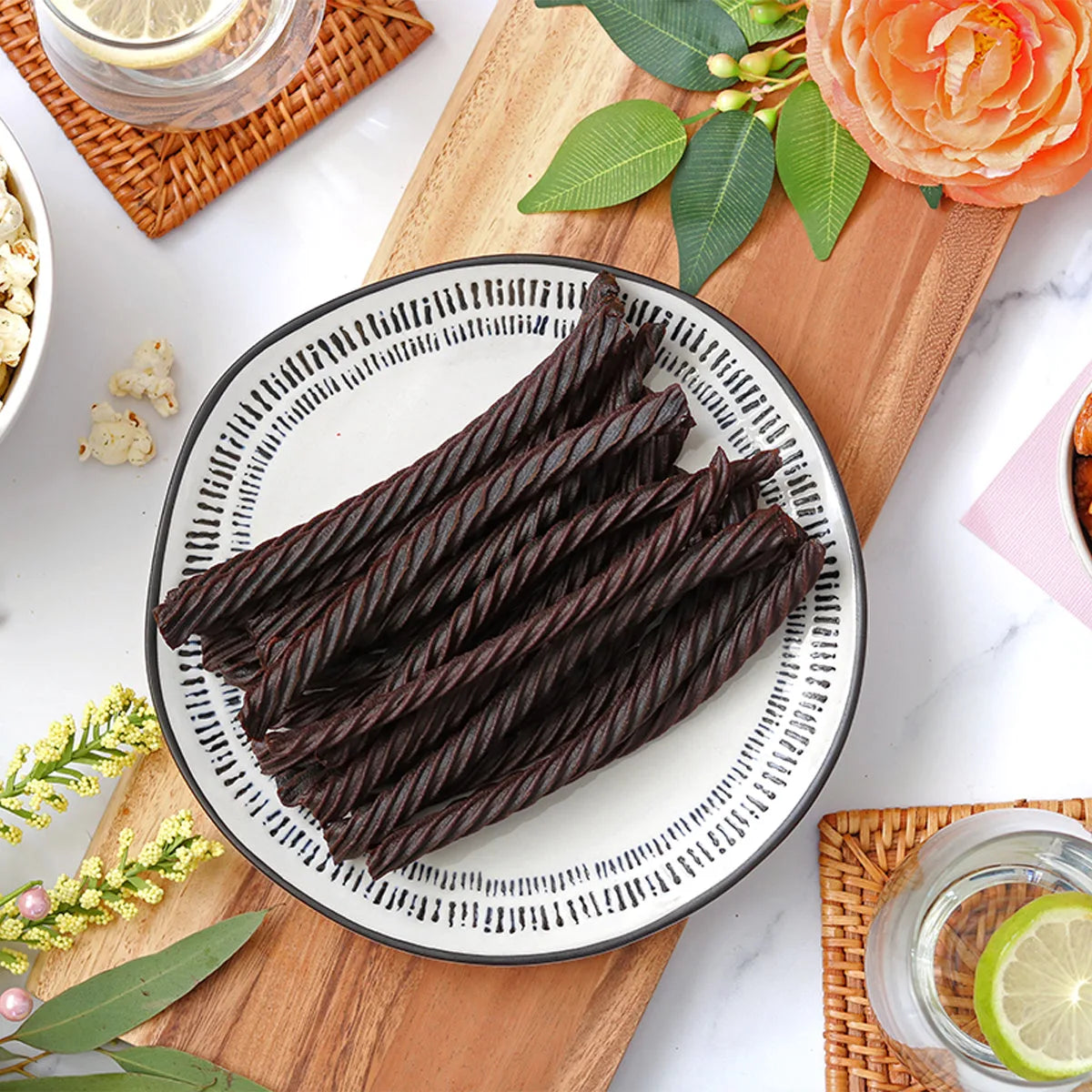 Red Vines Black Licorice Twists on a plate surrounded by spring flowers and other snacks