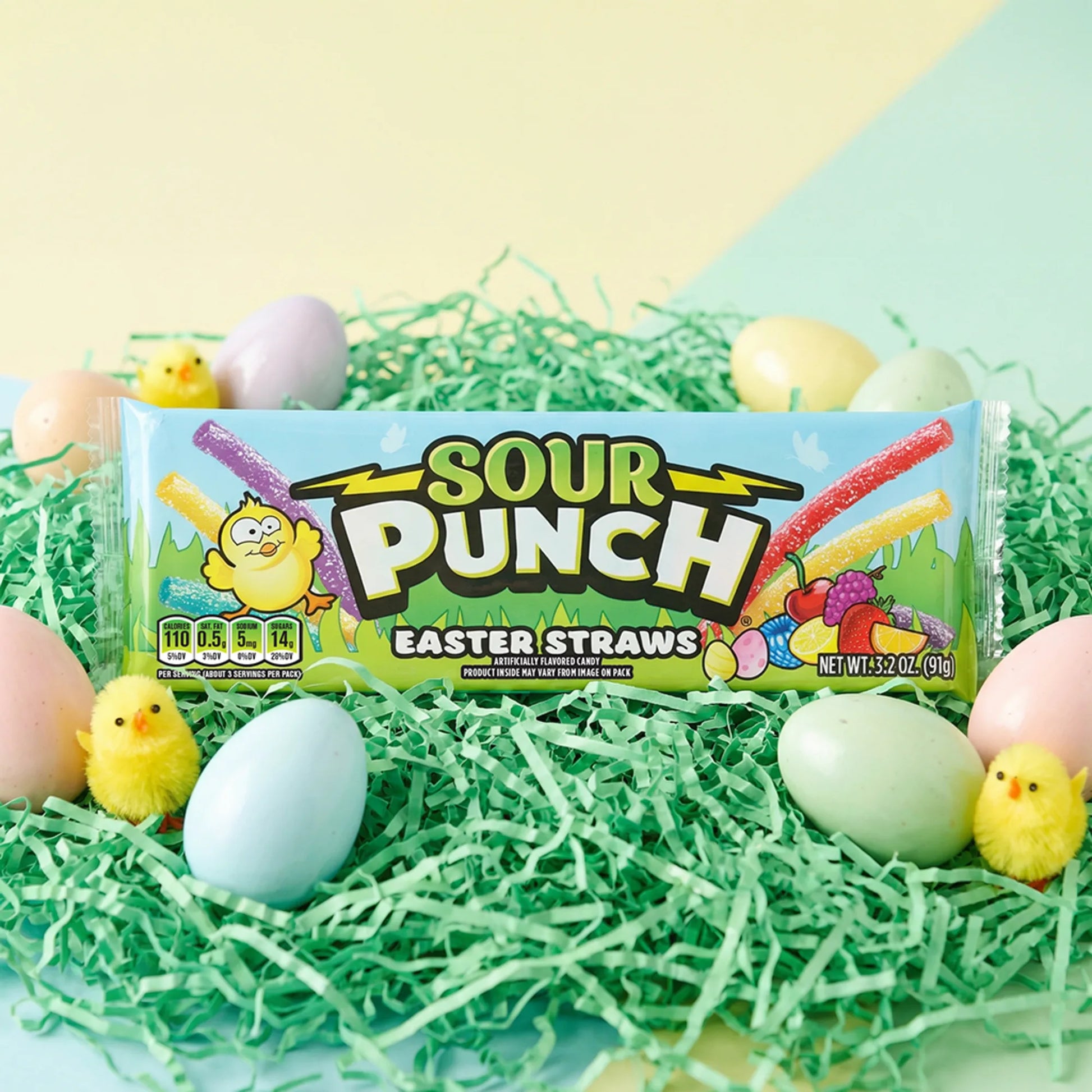 Sour Punch Easter Straws on grass-colored confetti, surrounded by dyed eggs and little chick toys