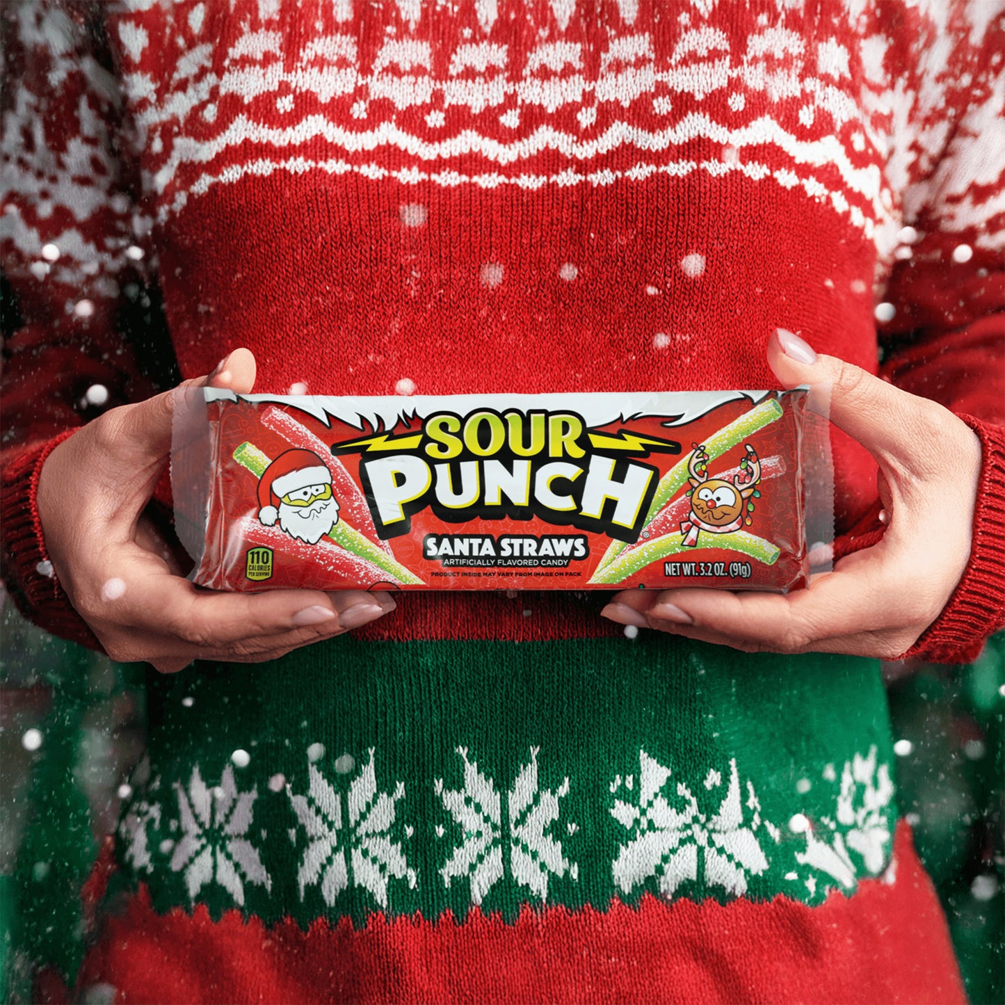 Man holding Sour Punch Santa Straws and wearing a Christmas sweater