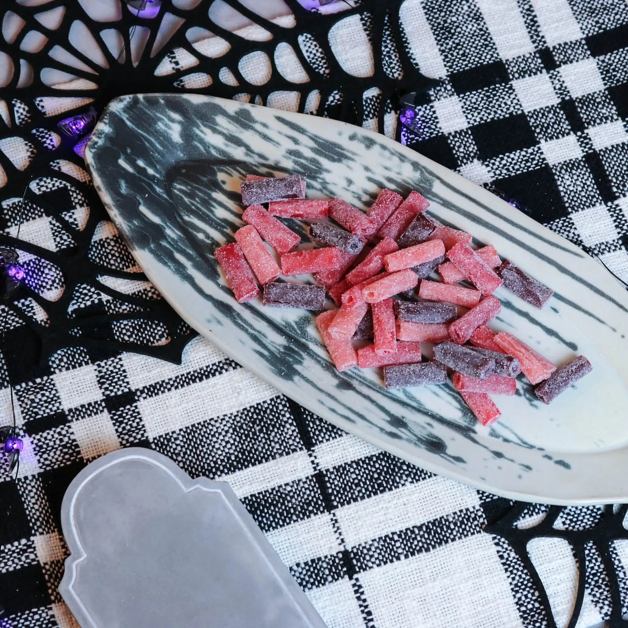 Sour Punch Rad Red Bites Candy on a platter with a fake spiderweb and tombstone