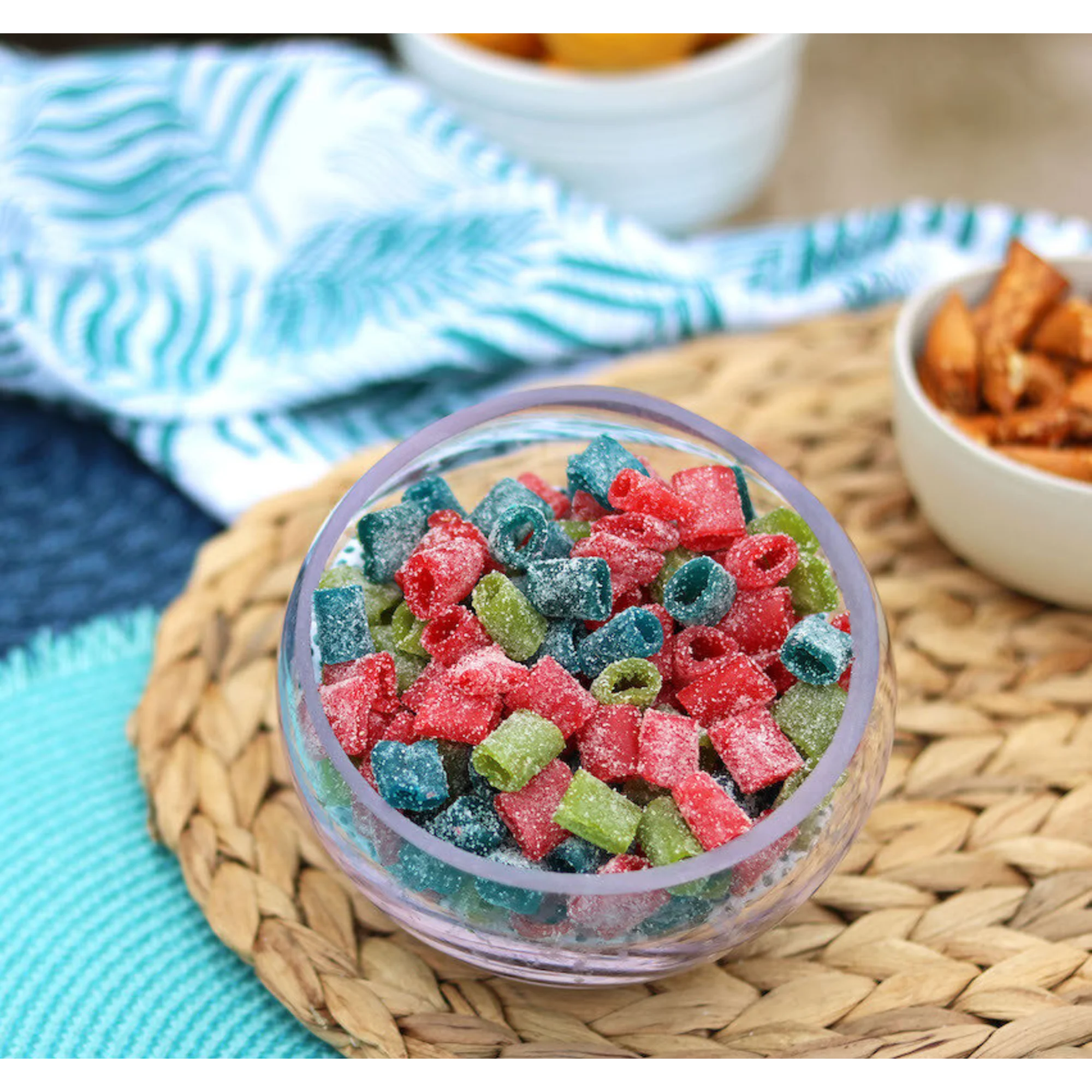 Bowl of Sour Punch Assorted Mini candy on a beach blanket with other salty snacks