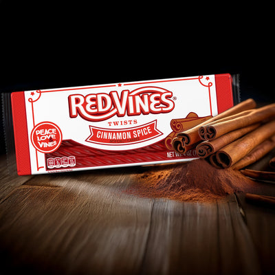 Red Vines Twists Cinnamon Spice 4oz Tray and cinnamon sticks on a pile of cinnamon spice powder