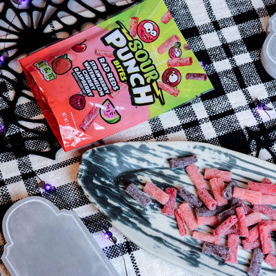 Sour Punch Rad Red Bites Candy on a platter with a fake spiderweb and tombstone