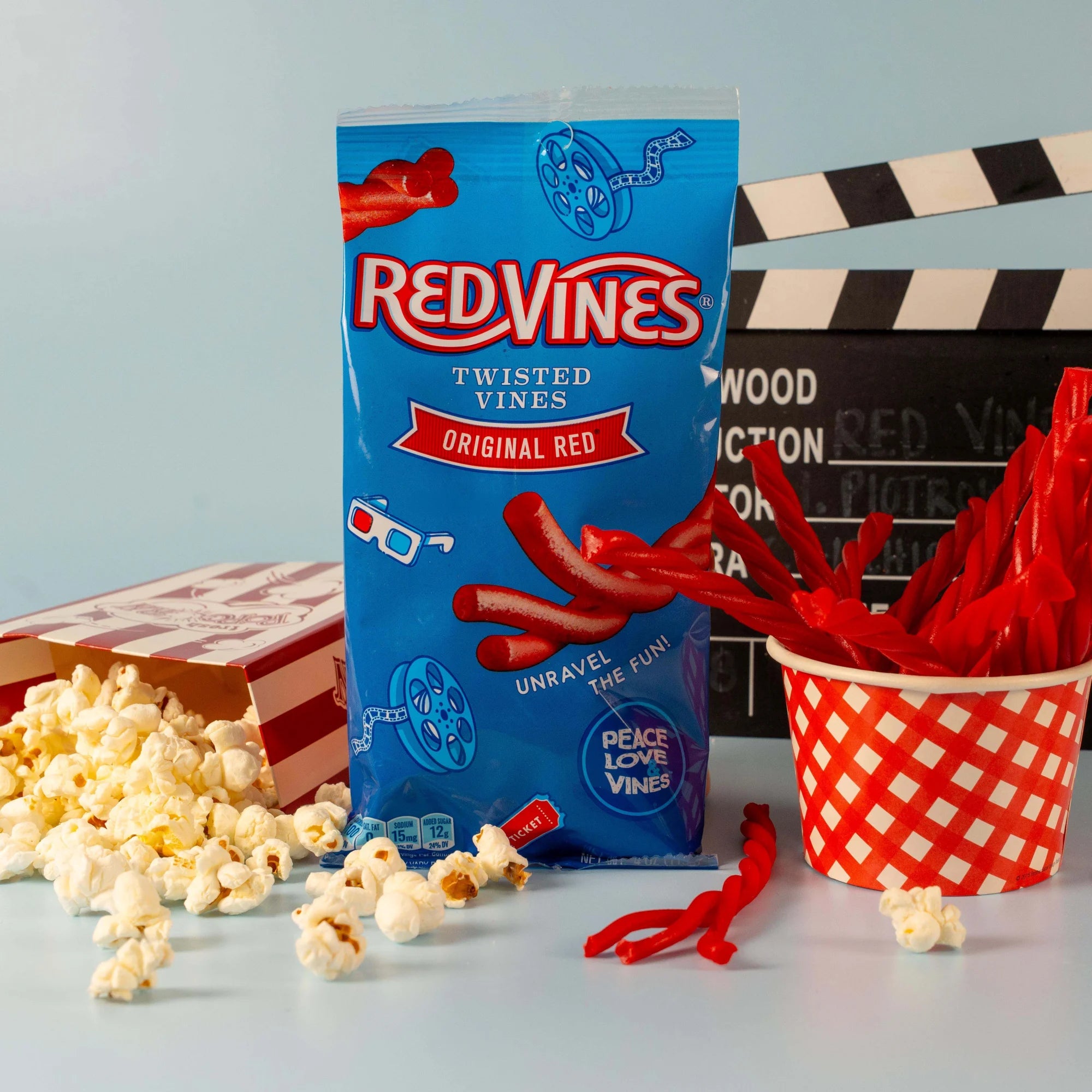 Red Vines Original Red Twisted Vines Candy 4oz Bag with a tub of popcorn and a cup of twisted red licorice candy pieces