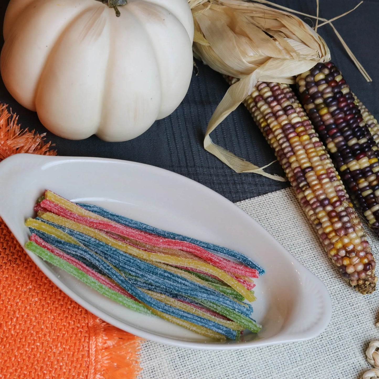 Sour Punch Rainbow Straws Candy in a white dish near a pumpkin and falltime props