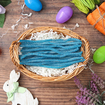 Sour Punch Blue Raspberry Straws candy in an Easter basket  surrounded by confetti and plastic eggs