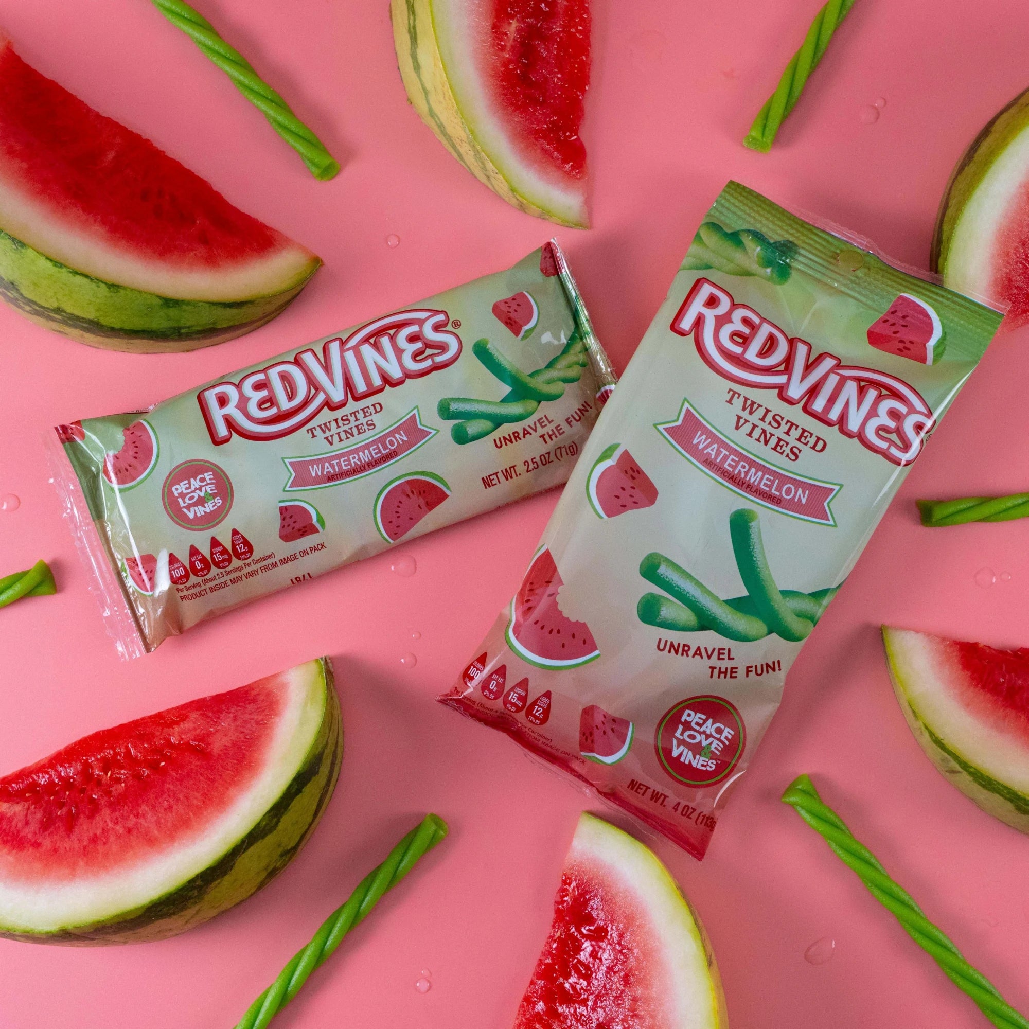 Red Vines Watermelon Twisted Vines 2.5oz and 4oz Bags on pink background with watermelon candy pieces and real watermelon fruit