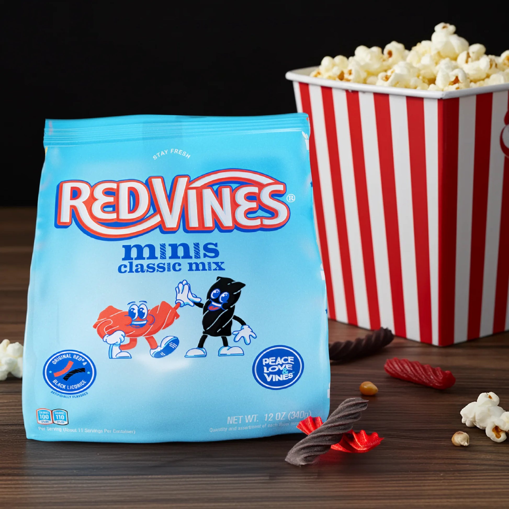 Red Vines Classic Mix Minis 12oz Bag with mixed licorice pieces in front of bag and a bucket of popcorn nearby