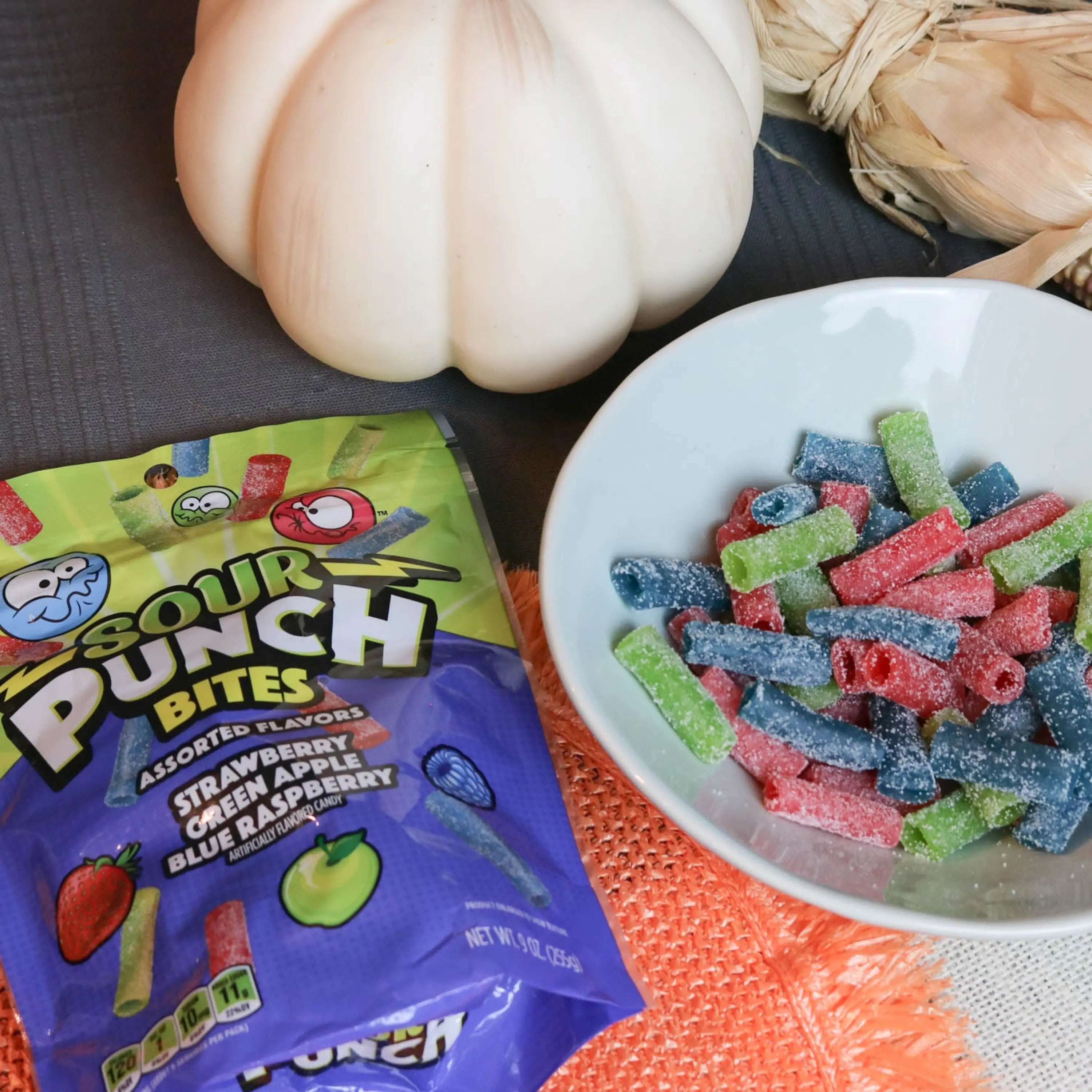 Sour Punch Assorted Bites Candy in a white dish near a pumpkin and falltime props