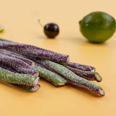 Half purple, half green ropes candy filled with white cream with a cherry and lime