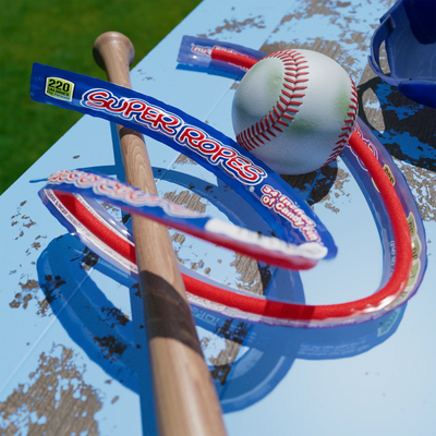 Super Ropes candy wrapped around a baseball and bat on a worn bench with grass in the background