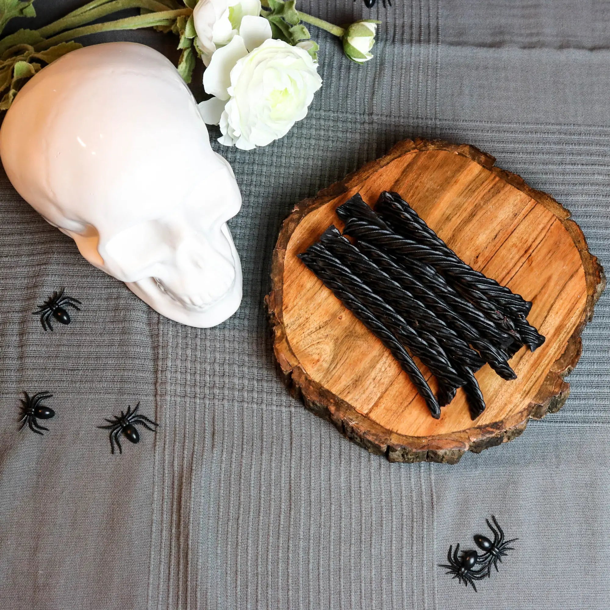 Red Vines Jumbo Black Licorice Candy in a spooky Halloween scene with fake spiders, a white skull and white roses