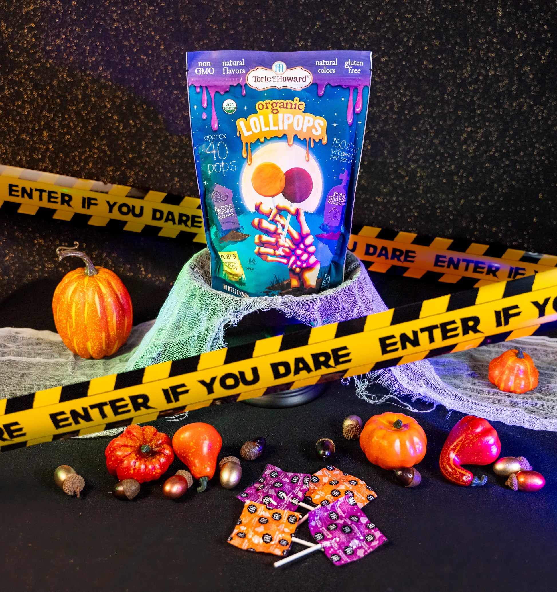 Organic Halloween Candy Lollipops surrounded by mini pumpkins and caution tape