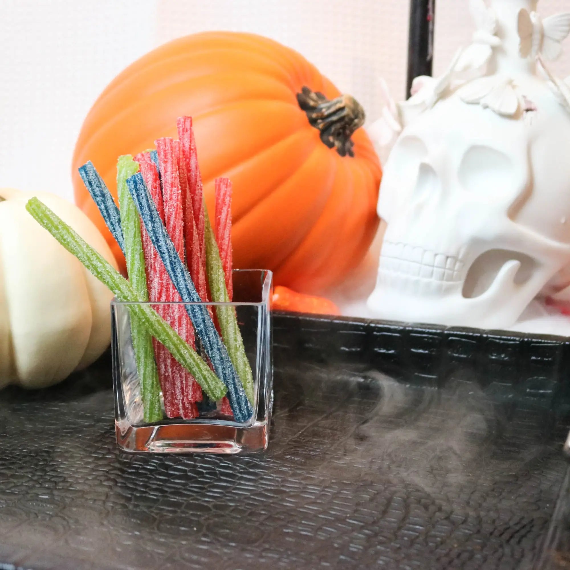 Sour Punch Individually Wrapped 6in Twists Assorted Candy on a black tray with pumpkins and fake skulls